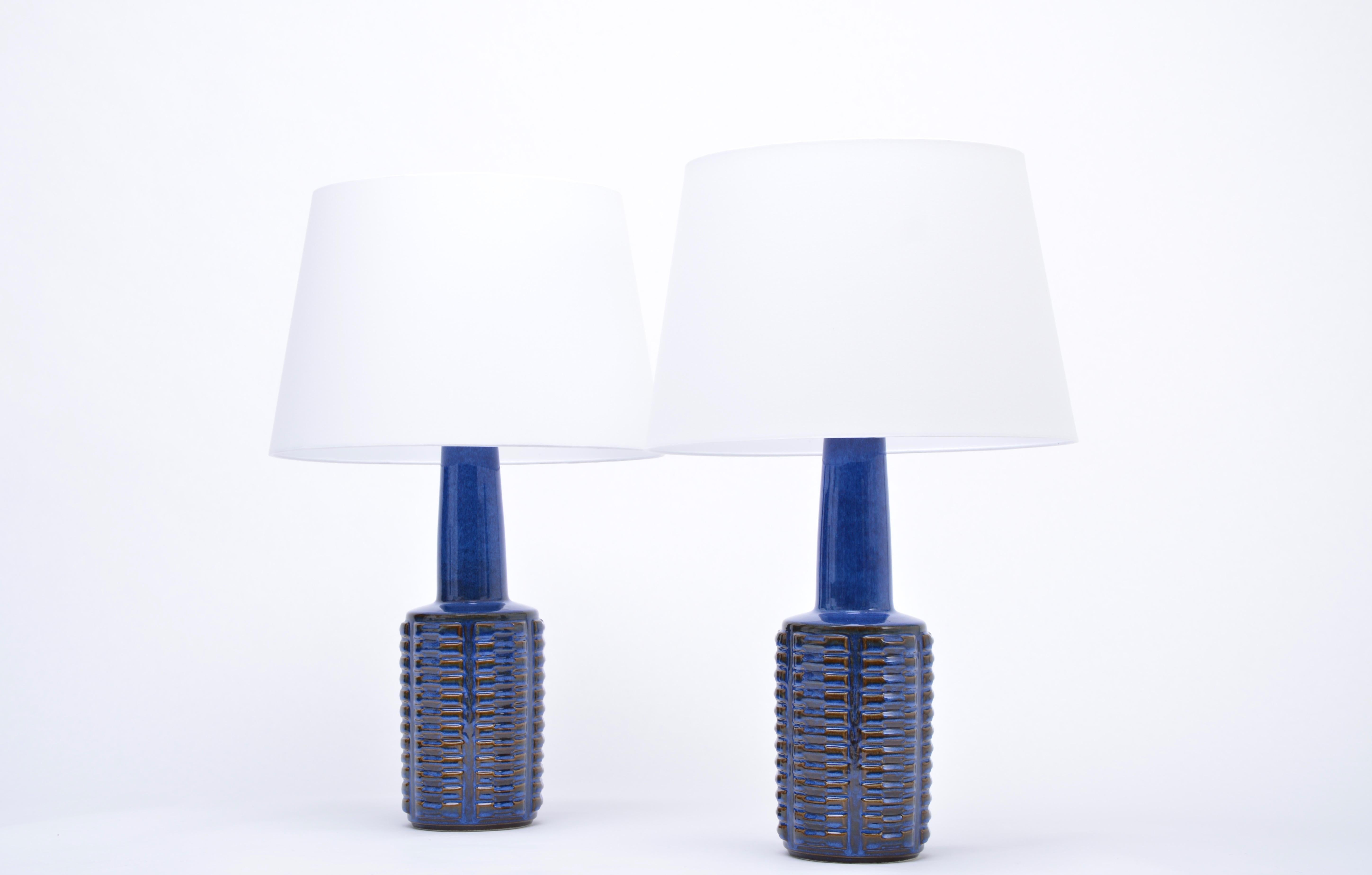 Pair of tall table lamps made of stoneware with ceramic glazing in different tones of blue. Graphic pattern to the base of the lamp. Designed by Einar Johansen and produced by Danish company Soholm. The lamps have been rewired for European use and