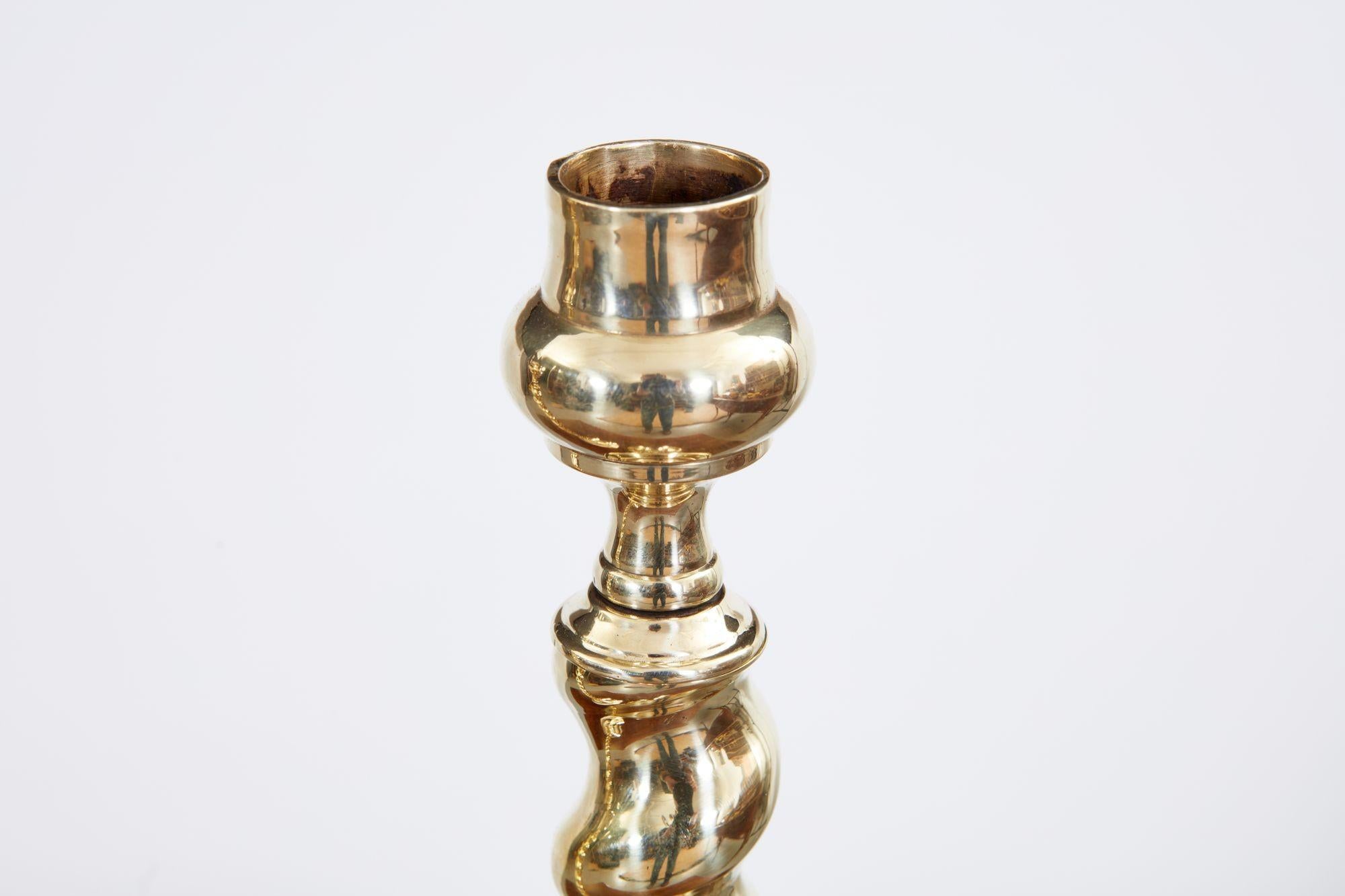 A pair of English late 19th century brass candlesticks with bulb tops over barley-twist shafts and standing on circular bases, having good scale.
