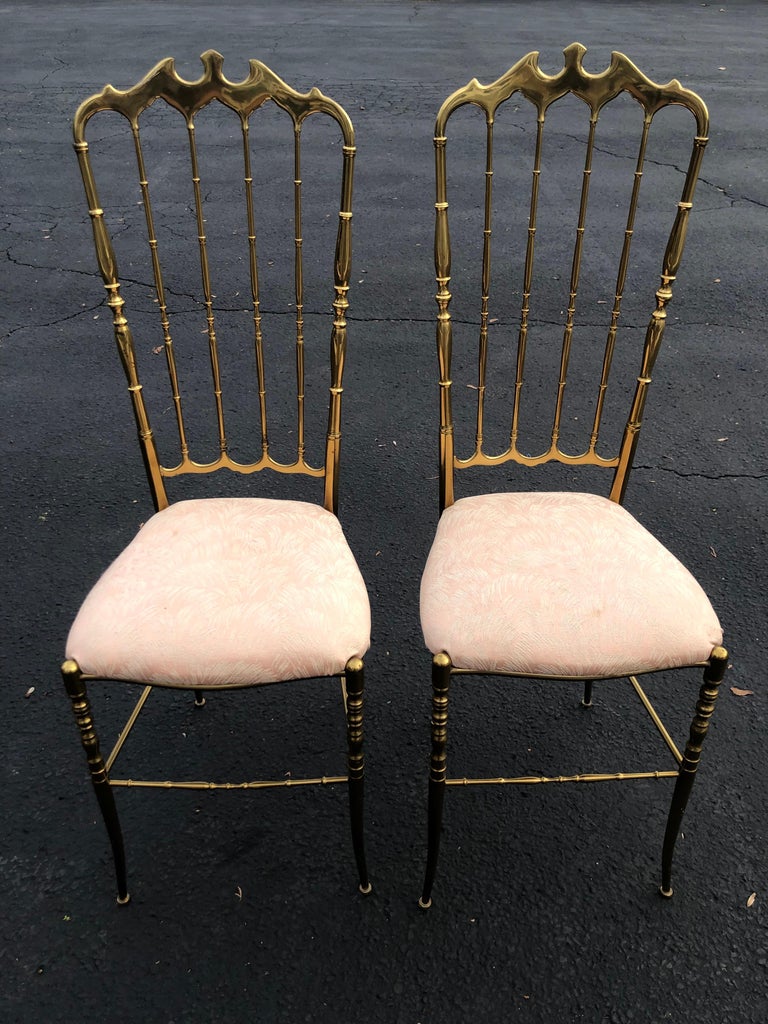 Pair of tall brass chiavari chairs. Exquisite and Feminine pair of Solid Brass Chairs. 
The chiavari chair, pronounced “ke-a-va're,” was created in Chiavari, Italy and named after the city of its origin. It was designed and built by cabinetmaker