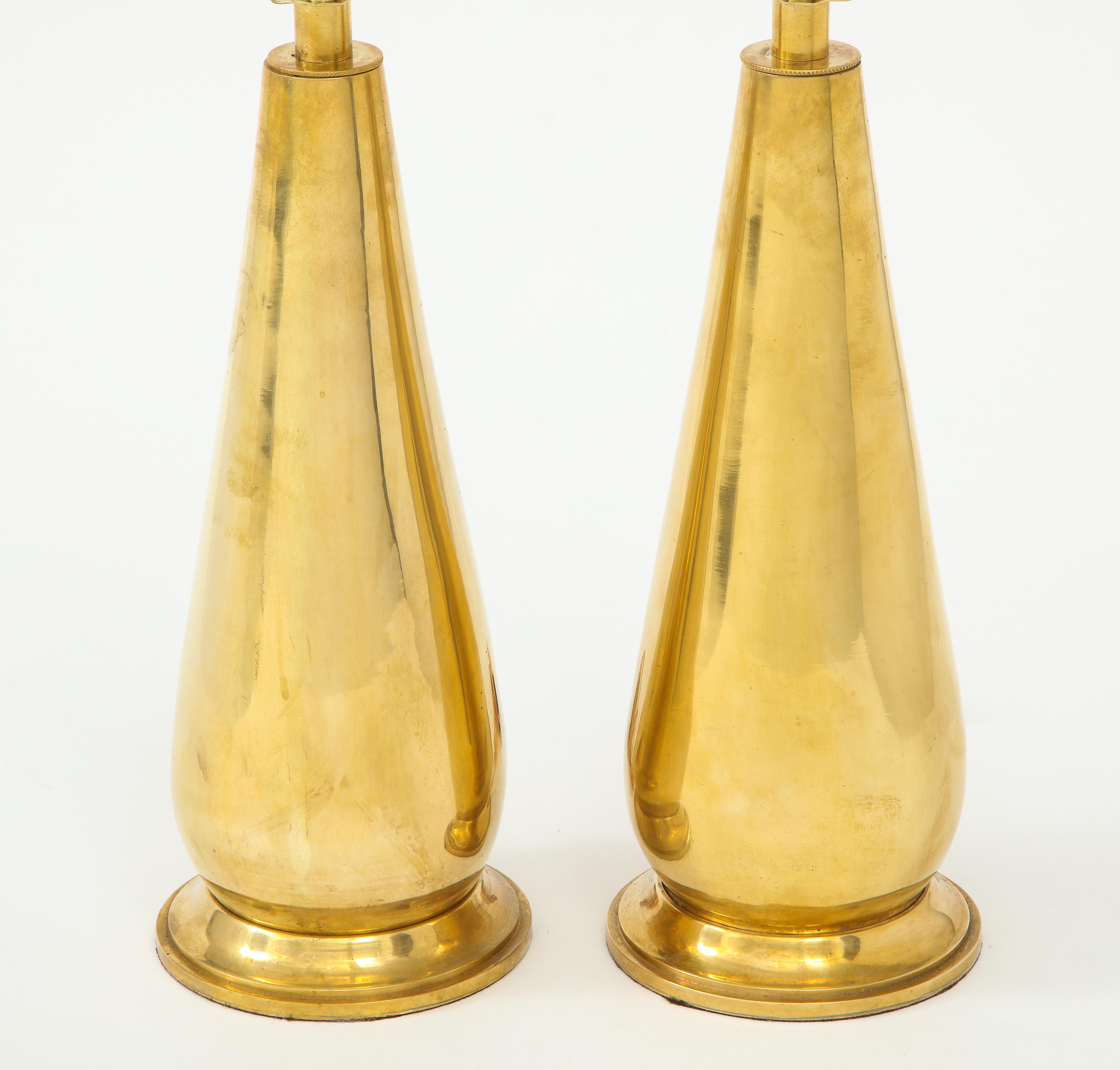 A stunning pair of brass lamps in a sleek teardrop shape on a brass base. Their vintage age gives them a lovely patina--a wonderful way to add a bit of shine and warmth to a room!