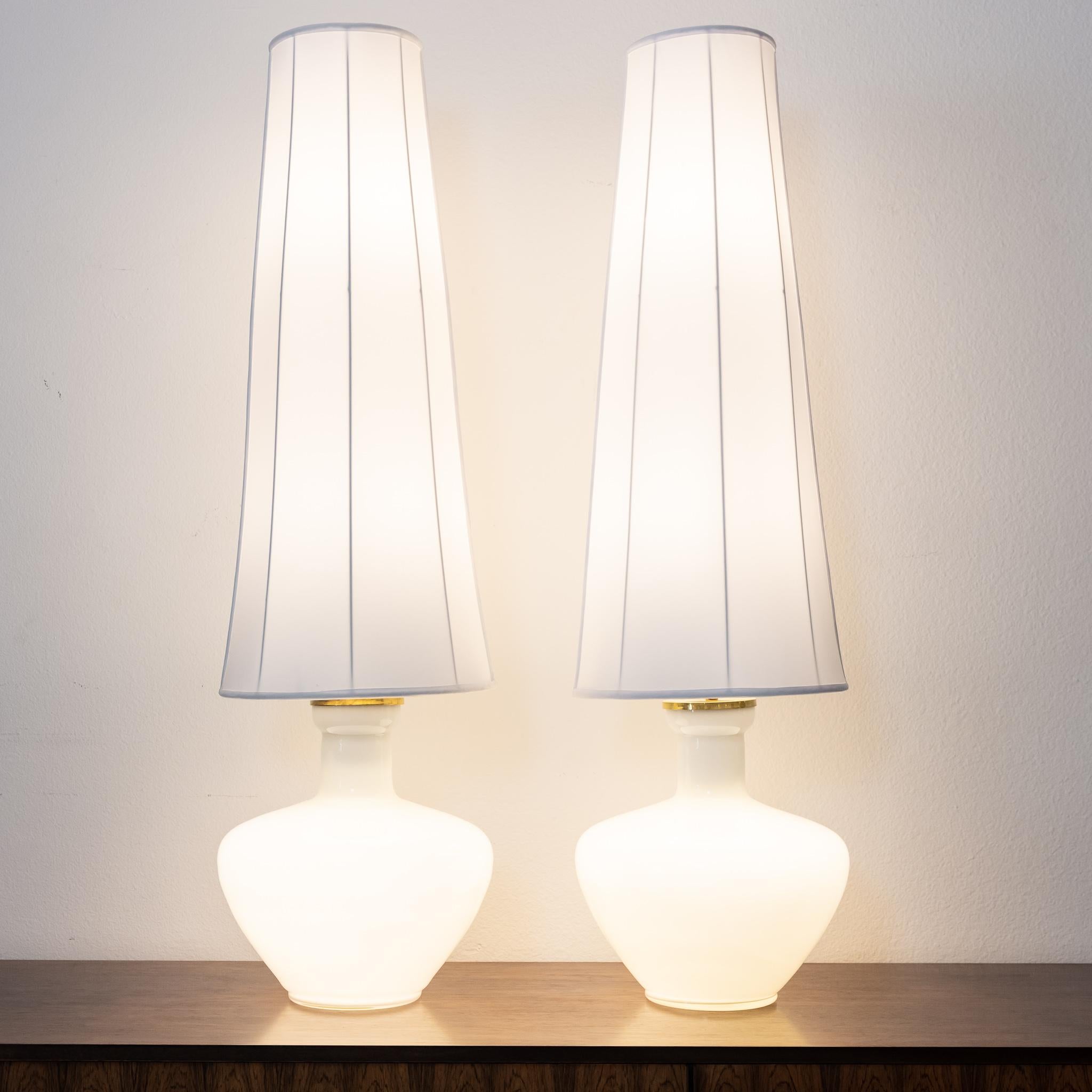 A unique and rare pair of lamps, circa 1940s, with Murano cased glass bases and original shade armatures. The new covering on the shades are beautiful hand sewn silk. A three way light switch illuminates the Murano bases, the lampshades or both