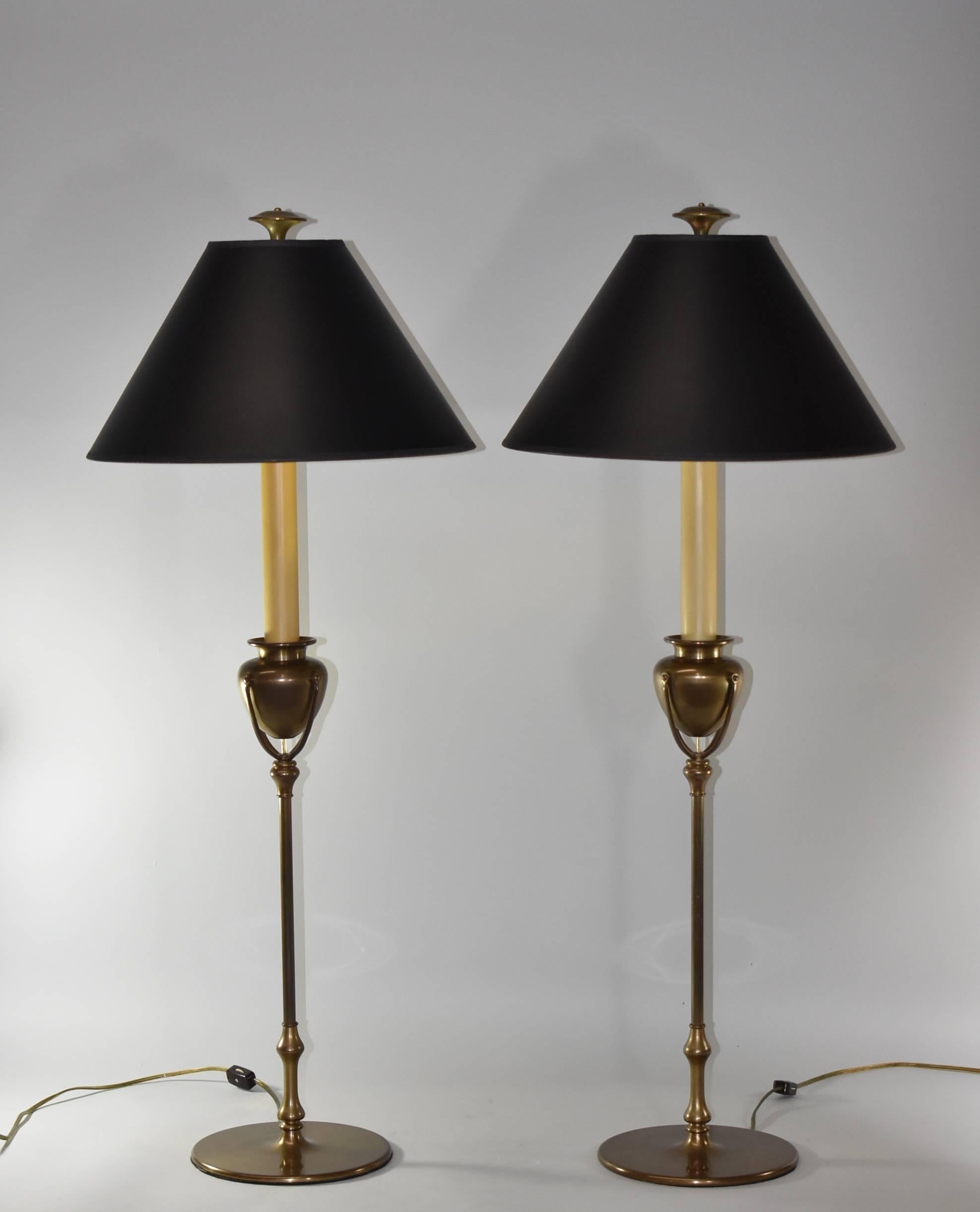 A lovely pair of brass buffet lamps by Chapman, 1985. These beautiful lamps feature a slender round brass candlestick body with an urn form centre.