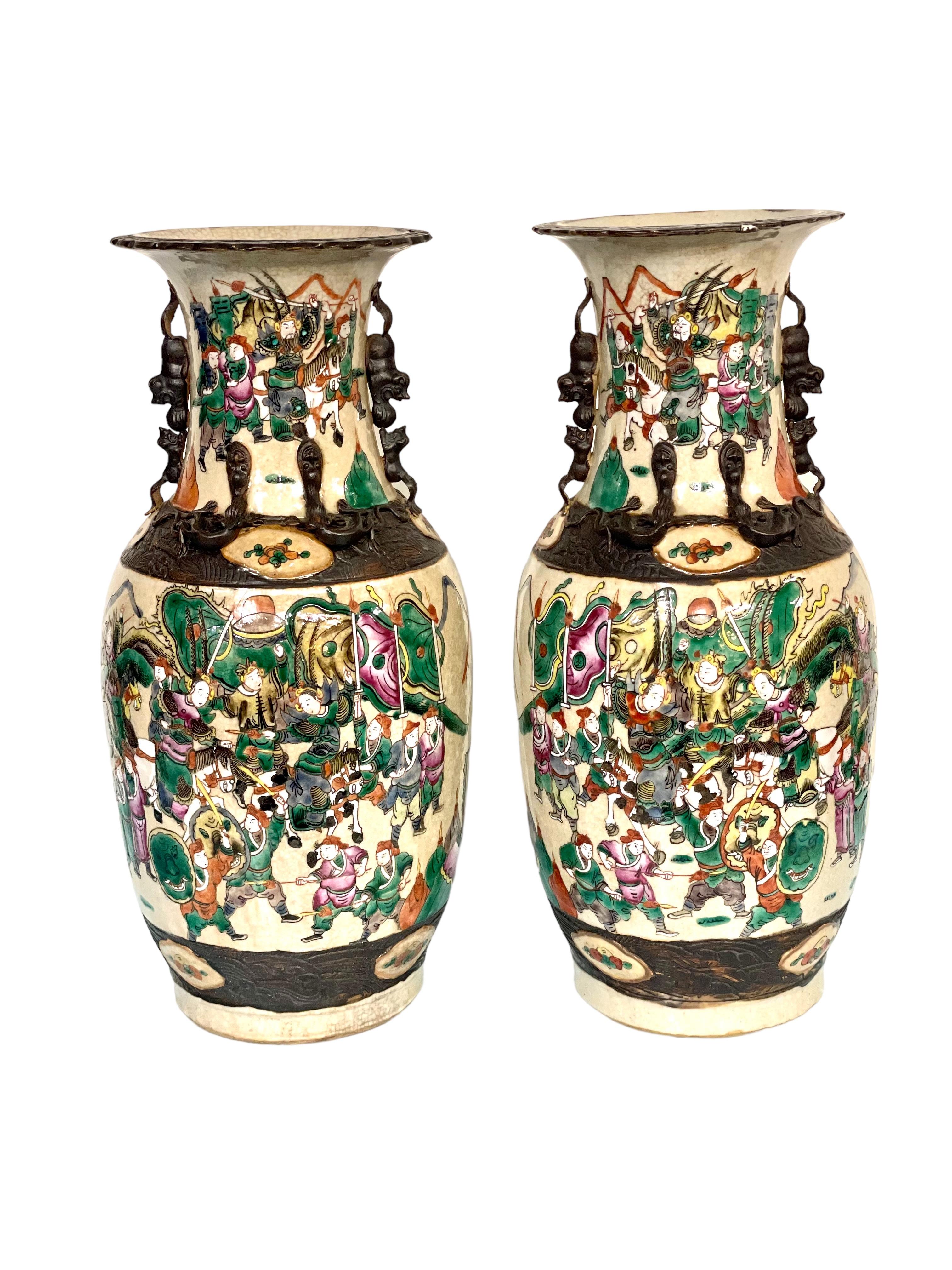 A superb pair of large and elegant Chinese 'Nanjing' porcelain baluster vases, each intricately decorated with an encircling battle scene of warriors on foot and on horseback on its lower half. Dating from the 19th century, these statuesque crackle