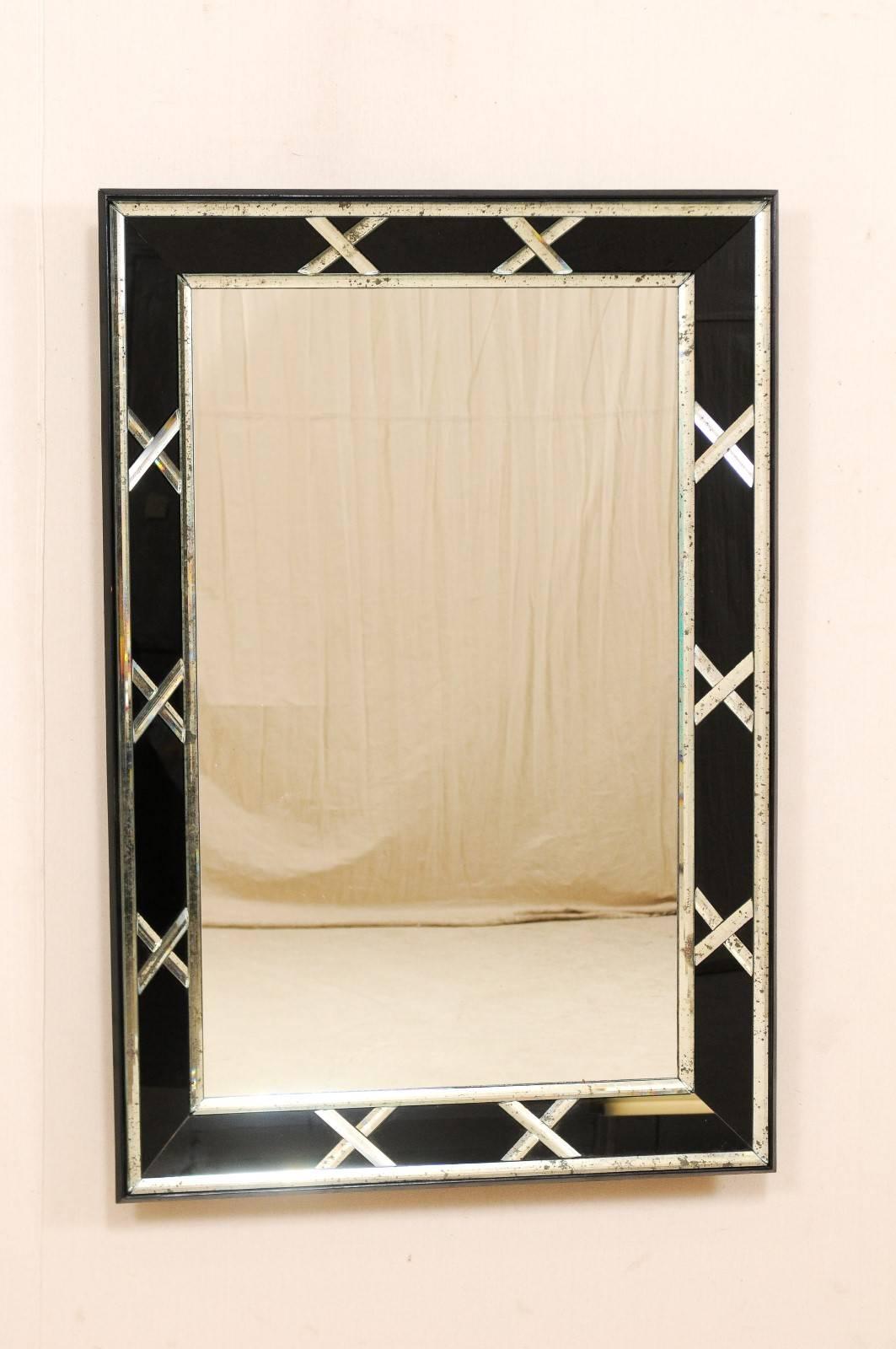 A pair of vintage American large-sized mirrors with accentuated black X-designed border. These American rectangular shaped mirrors feature a clear center glass center with black glass surround which is accented in an x-shape motif and framed along