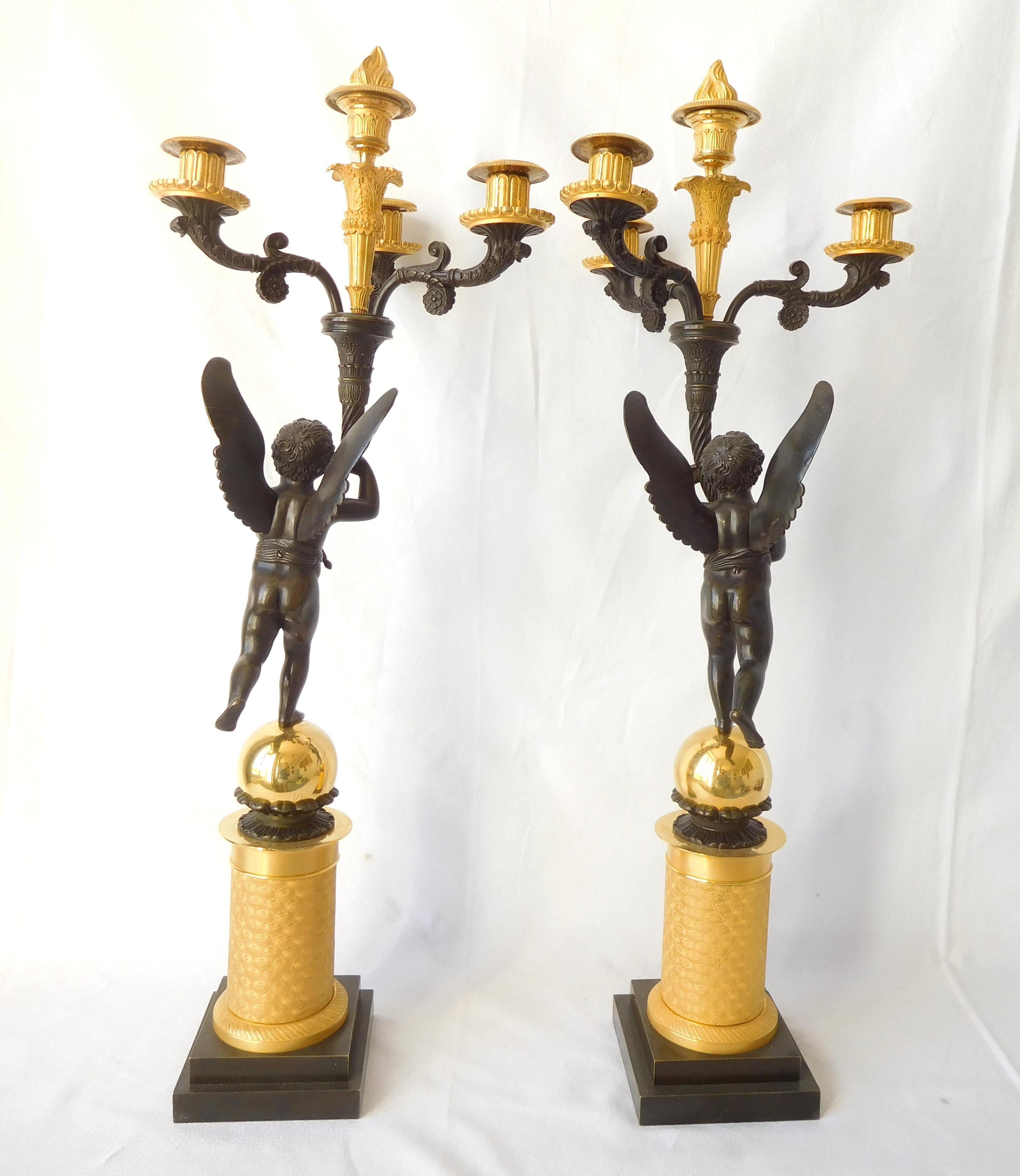 Paire de grands candélabres en bronze doré (mercure) et bronze patiné, production française de la Restauration, début du 19e siècle, vers 1815 - 1820.
Spectaculaire modèle à 4 lumières tenu par des putti ailés reposant sur une base en forme de