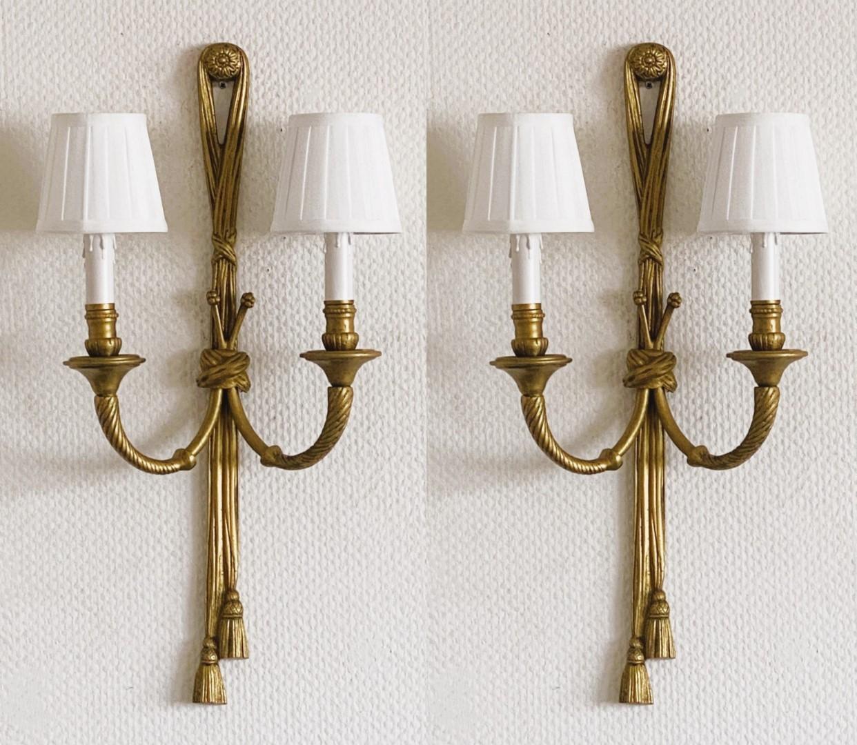 A very elegante pair of tall Louis XVI style gilt bronze wall sconces, France, early 20th century. Two light-arm richly decorated with scrollwork foliage, bottom ending in Tassel & Ribbon form. High quality solid bronze fire-gilded finish,