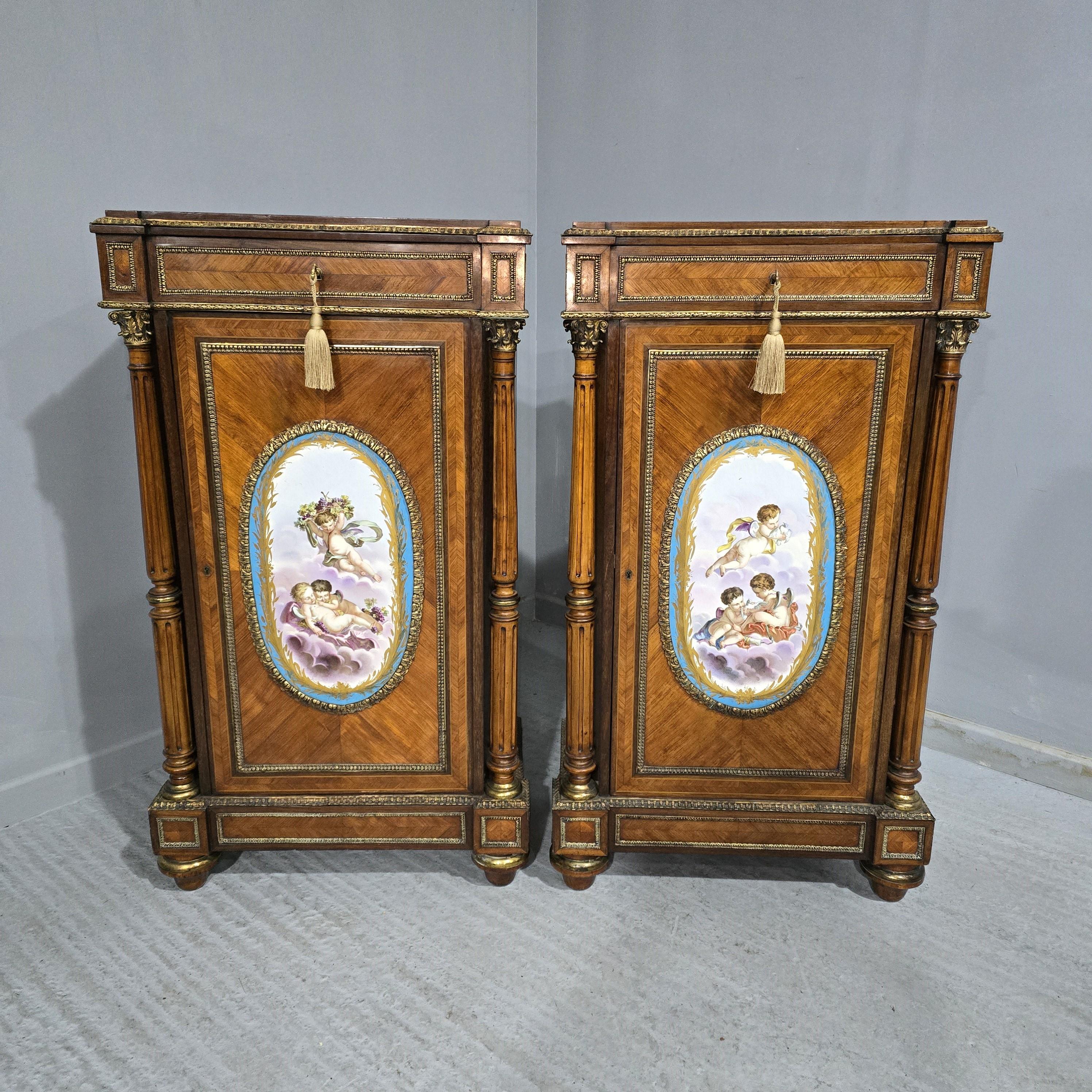 Maravillosa pareja alta de armarios franceses Luis XVI de madera de rey con destacadas placas ovales de porcelana de estilo Sevres que representan querubines, cubiertas con monturas doradas de ormolina, cada uno con un solo cajón y tres estantes