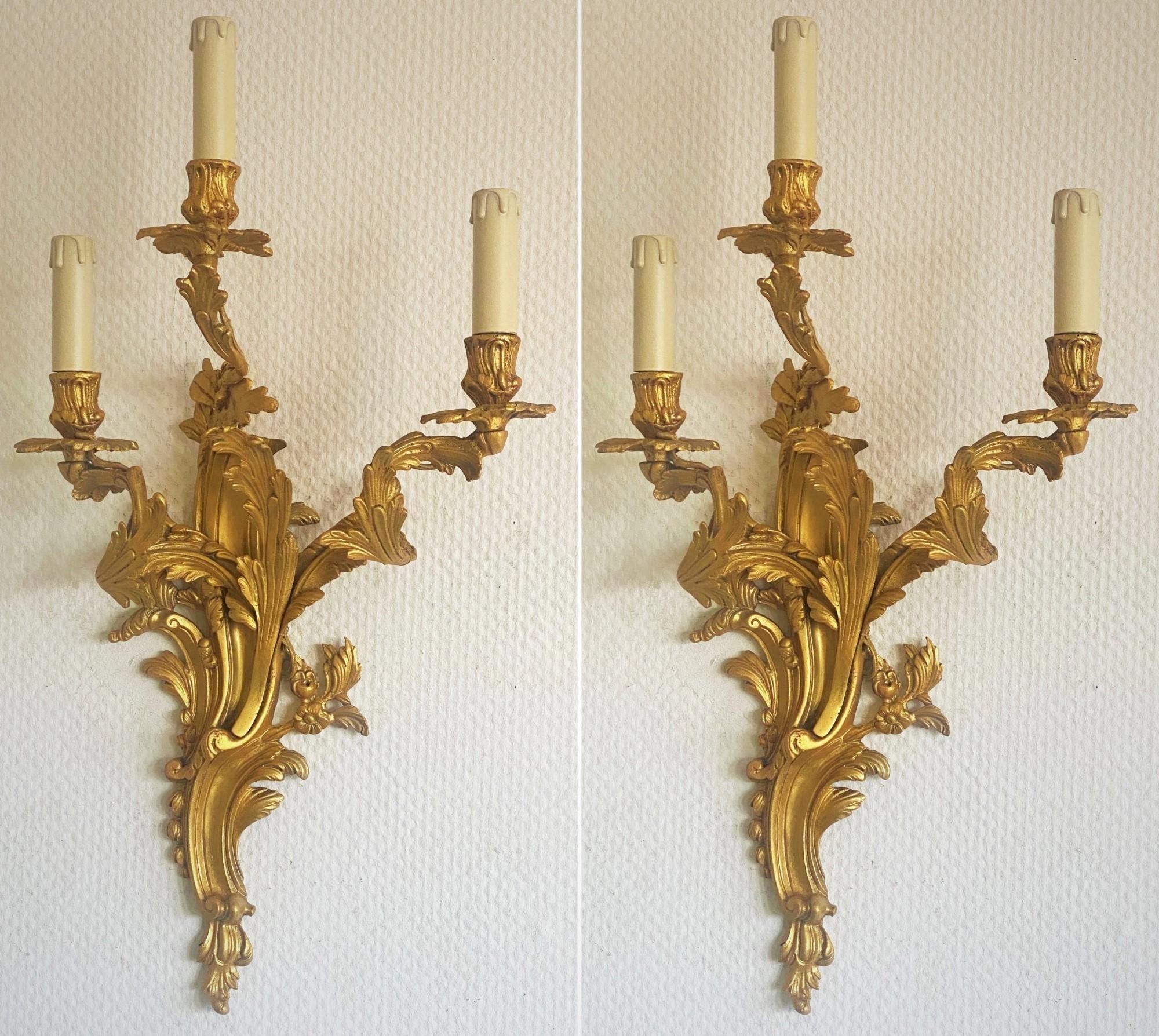 Pair of heavy, tall Louis XVI style gilt doré bronze electrified wall sconces, three-arm richly decorated with scrollwork foliage, France, late 19th century. High quality solid doré bronze fire-gilded finish, professional electrified at a later time