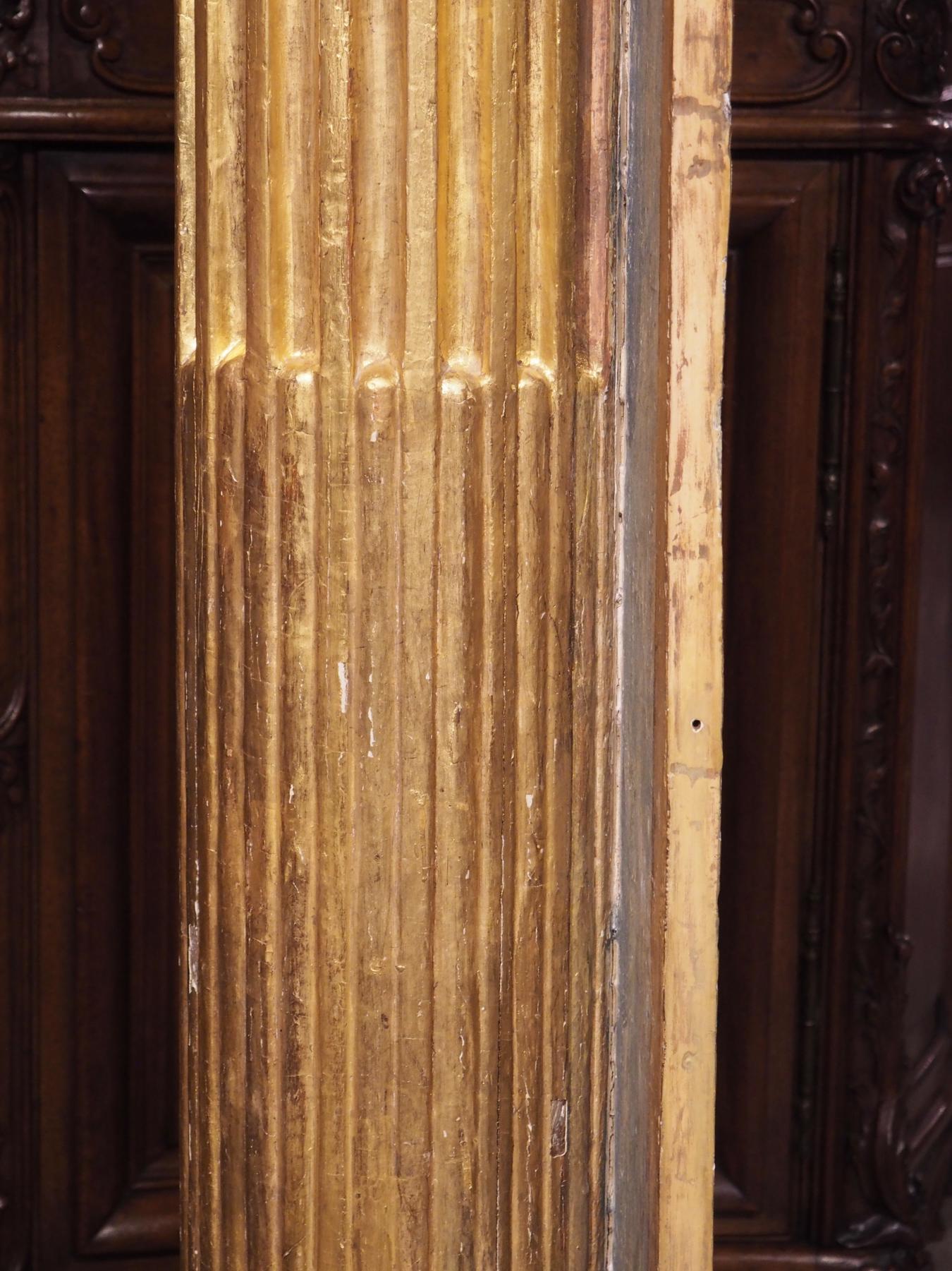 Hand carved in France, circa 1810, this pair of tall Neoclassical giltwood columns was inspired by the Corinthian order. Both of the ¾ columns (meaning they are not complete cylinders) are affixed to a single oak plank. The edges of the board have