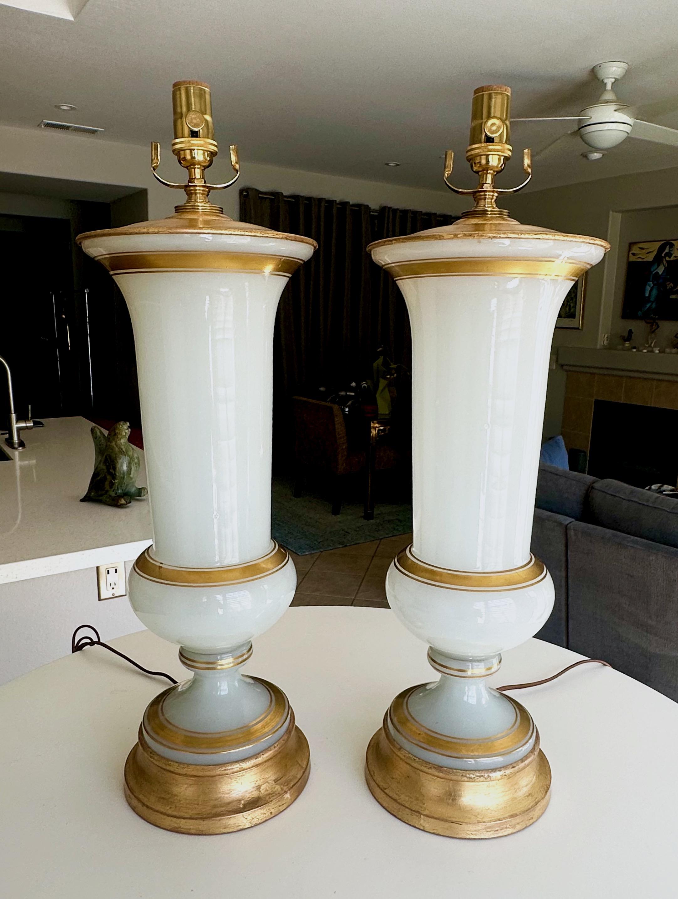 Paire d'élégantes lampes de table en verre blanc opalin soufflé à la main, montées sur des bases en métal doré à la feuille. Le verre, fabriqué par des experts, est orné de détails appliqués en or 23k. Le bouchon du vase en métal supérieur est
