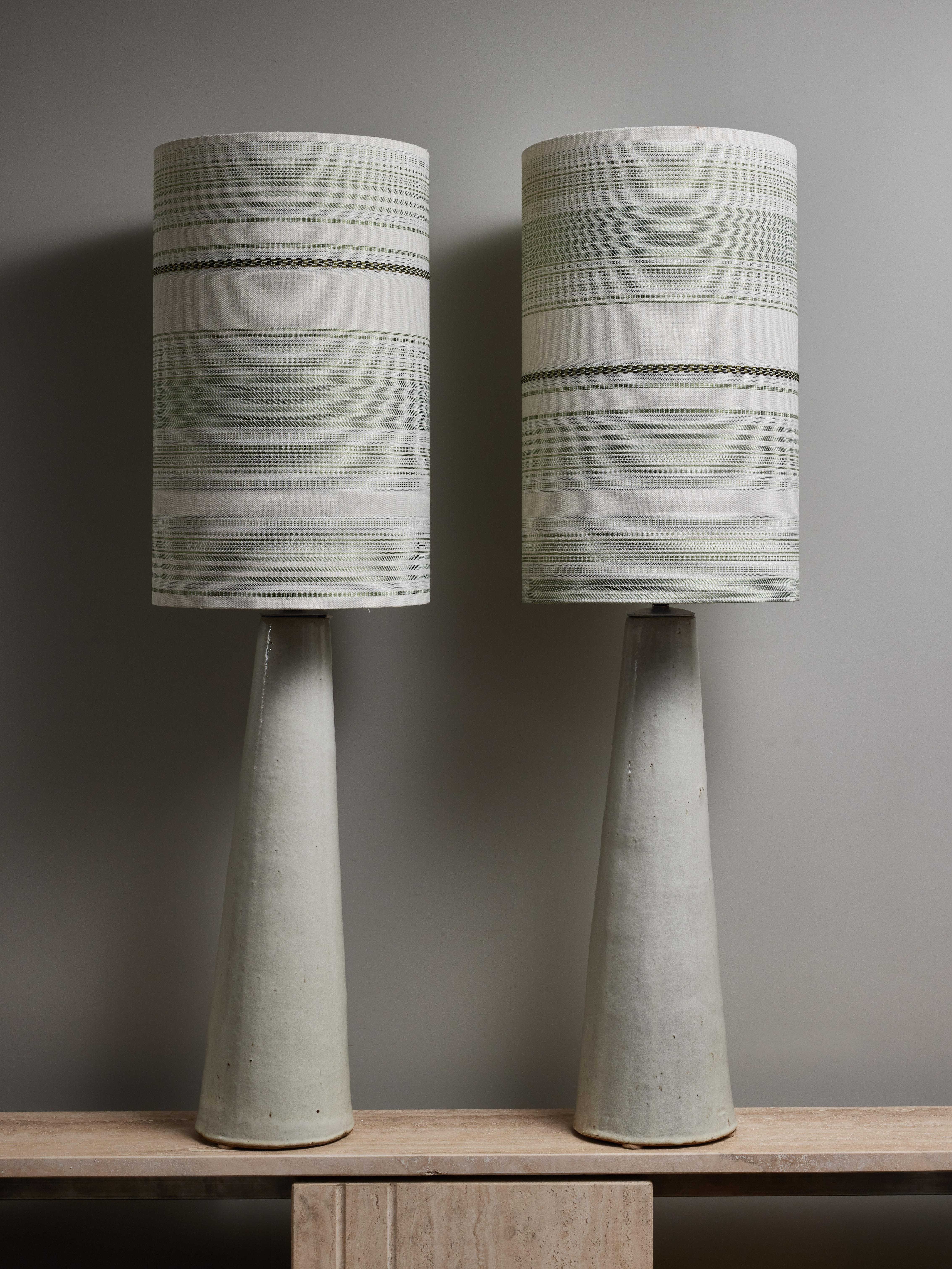 Pair of impressive tall ceramic table lamps, made of a single conical piece, glazed in an off white colour. Topped with a new lampshade.

Height with the shade: 140cm