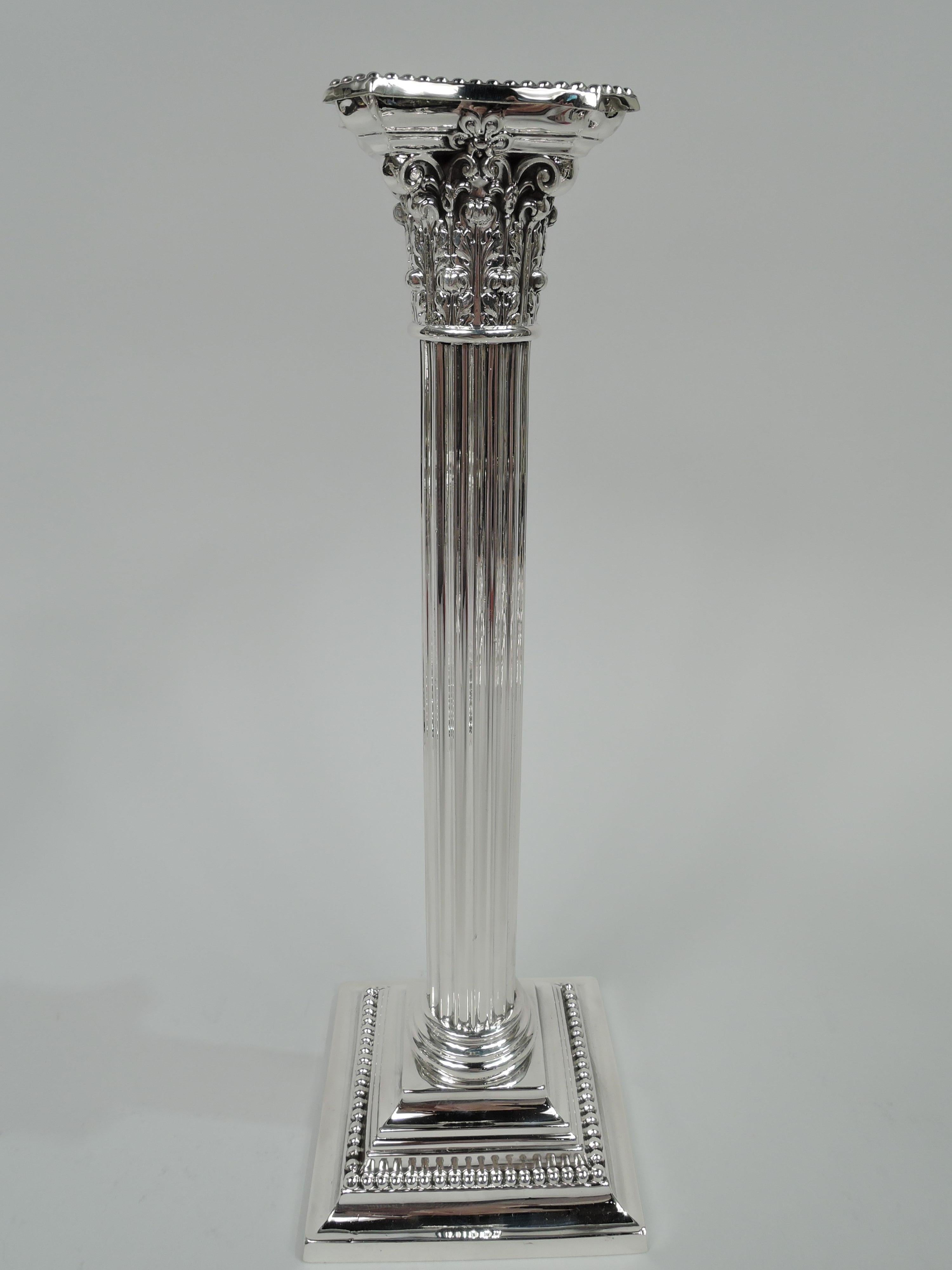 Pair of tall Neoclassical sterling silver candlesticks, circa 1940. Made by Gorham in Providence. Fluted columnar shaft on stepped square base. Composite Corinthian capital with detachable, concave, and chamfered bobeche. Beading. Fully marked