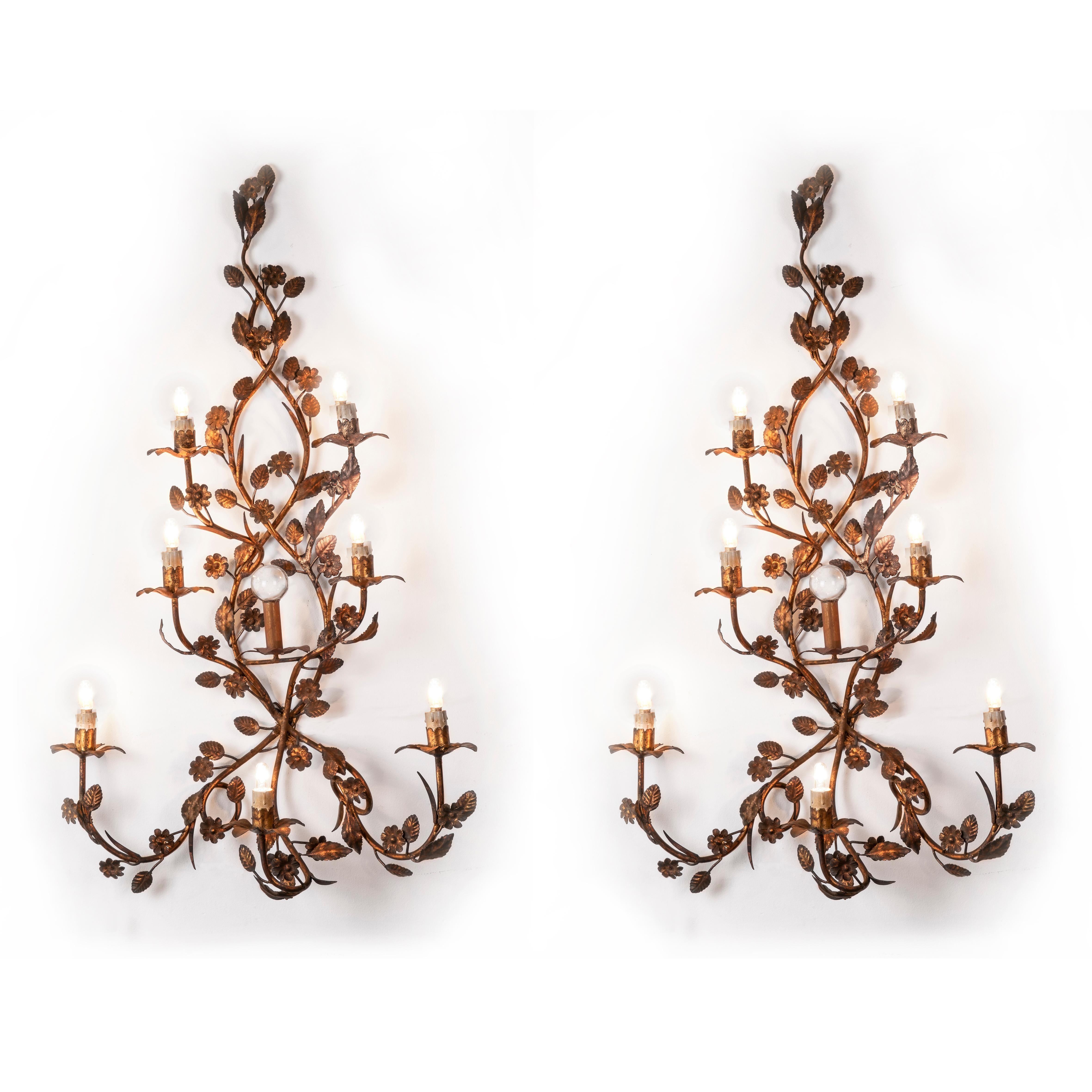 Pair of antique seven-light wrought iron wall lights dating back to the mid-20th century, consisting of two wrought iron branches, decorated with flowers and leaves, creating a slight pyramidal structure.
The seven curved arms ending with floral