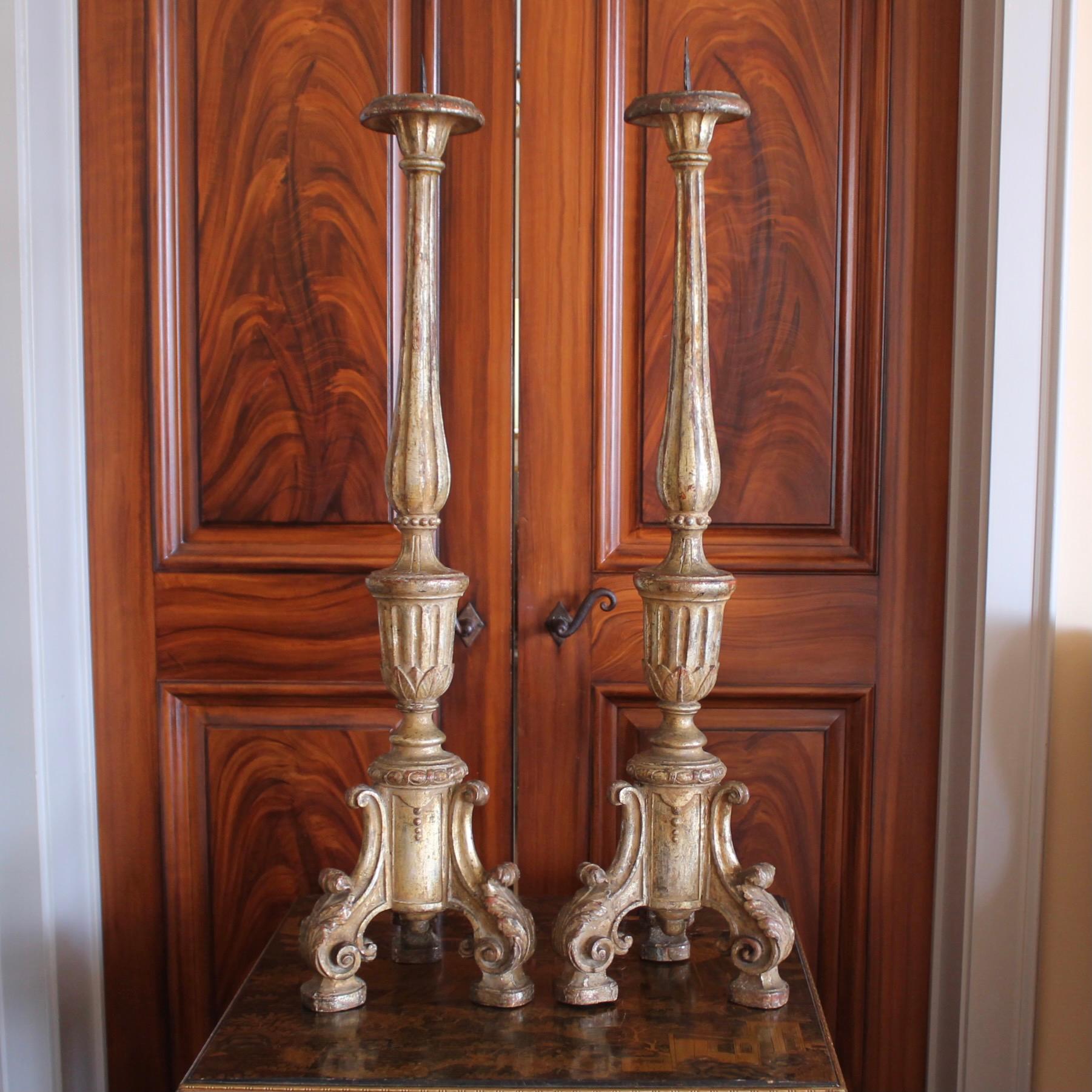 A fine pair of 18th century tripodal prickets with bold fully three dimensional feet forming the base, each supporting a fluted baluster terminating in the flared flat top. Lovely details such as the finley scrolled feet, gadroon carving and