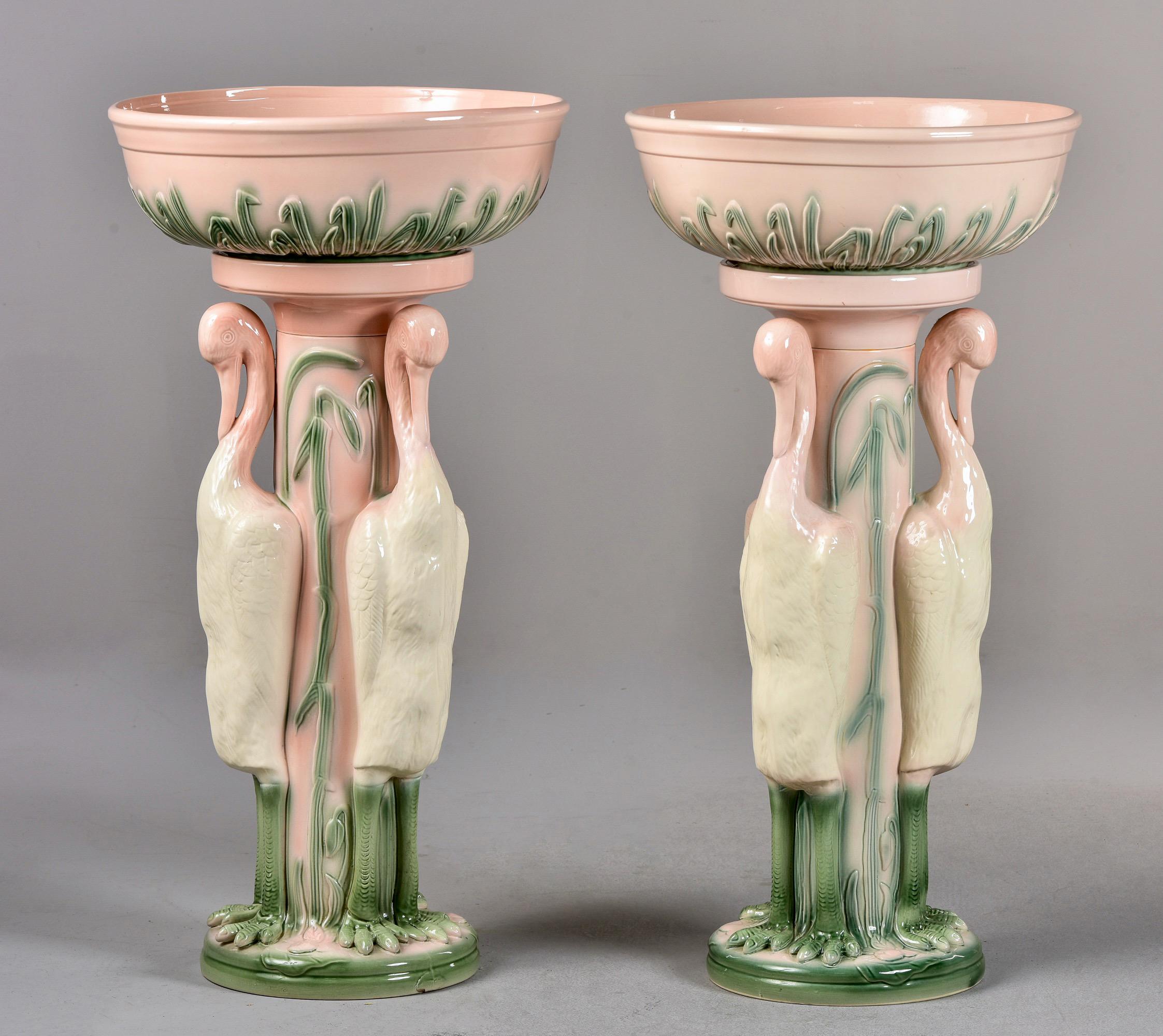 Circa 1970 pair of English tall porcelain flamingo jardinieres signed by Blakeney of England. Each jardiniere features a base surrounded by three standing flamingos and a large, removable bowl. Assembled, each jardiniere is 31” tall. One of the