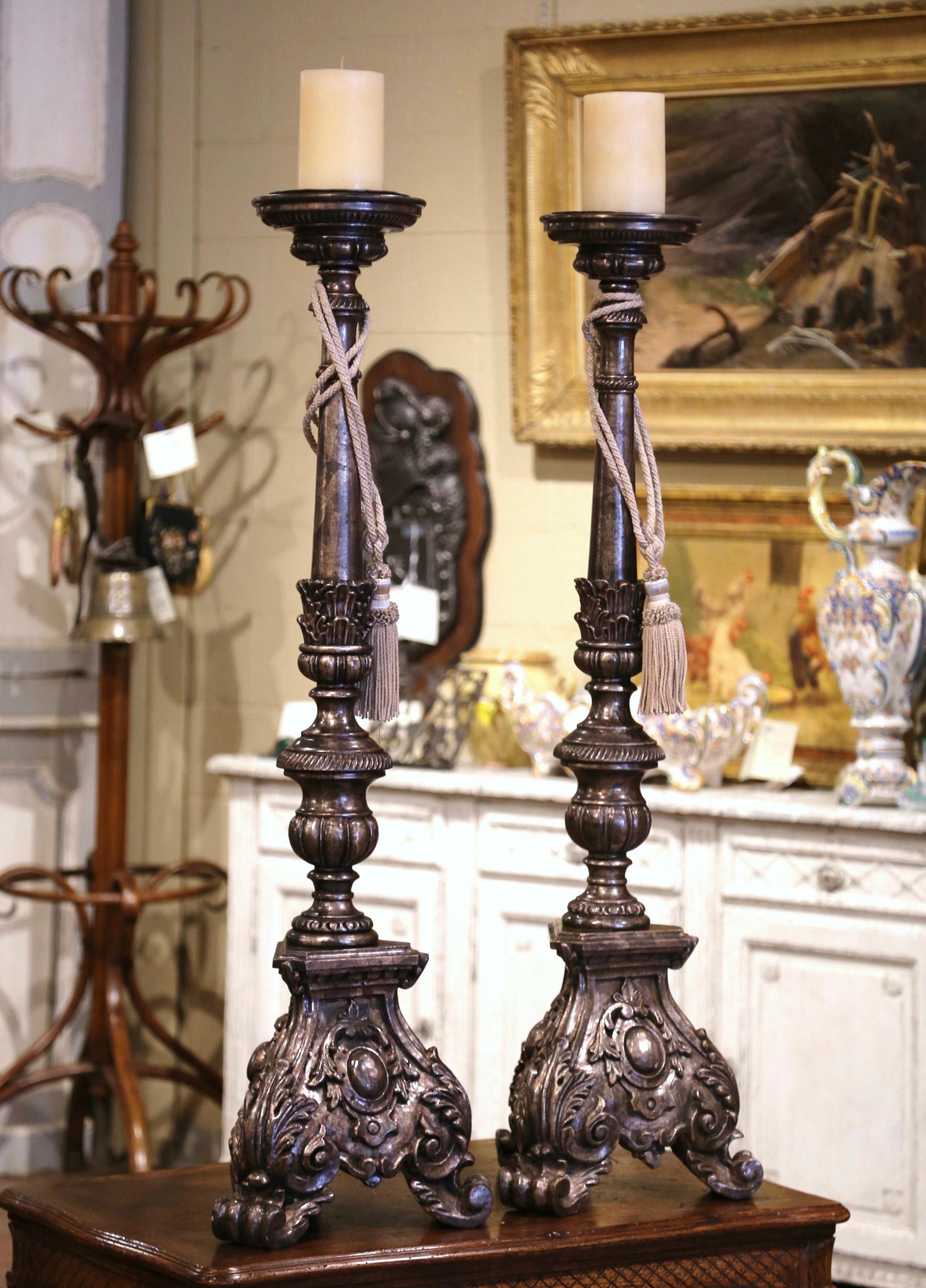 Add an air of drama and elegance to your home with this important pair of antique candlesticks. Crafted in Italy circa 1960 and almost four feet tall, each candle holder stands on a sturdy triangle base with hand carved acanthus leaves over three