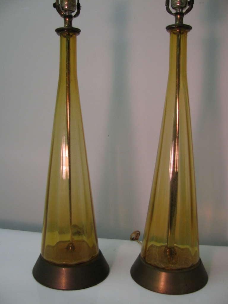 Pair of tall Italian midcentury, hand blown lamps in amber glass. Simple, elegant design. Lamps have vertical panels in a bottle form. Shades are excellent and appear to be original, which have a striae pattern running throughout creating a wood