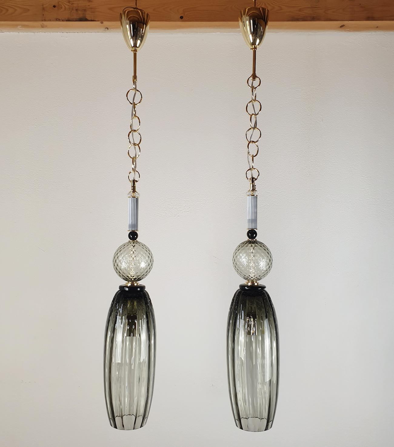 Very tall pair of Mid-Century Modern pendant lights, in a beautiful quality and handmade Murano glass. Italy 1990s.
The pair of pendants are made of several parts in Murano glass, in different shapes and colors: clear, gray, silver.
The last