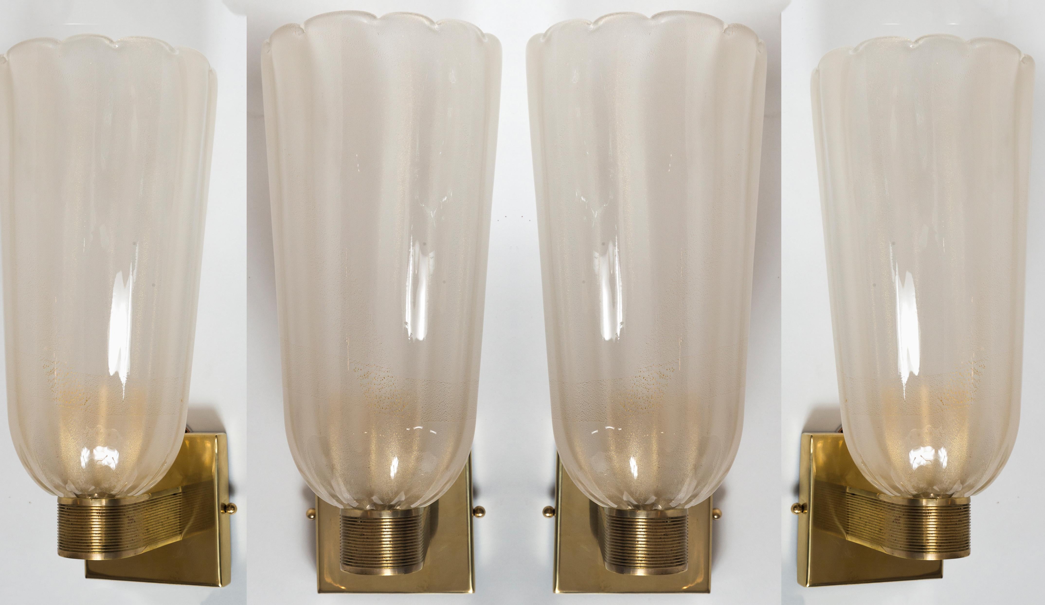 Un'elegante coppia di applique a bocca in stile Art Déco modernizzato, composta da coppe lattimo dorate alte e leggermente smerlate sostenute da eleganti bracci in ottone non laccato.

Cablato con porcellana E26, pronto per l'installazione con