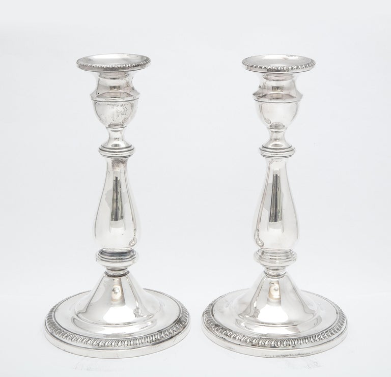 Pair of tall, Neoclassical-style, sterling silver candlesticks, The Mueck Carey Co., Inc., New York, Ca., 1930's-1940's. Each candlestick measures 9 inches high x 4 3/4 diameter across base. Weighted. Reeded motif on border of the base of each