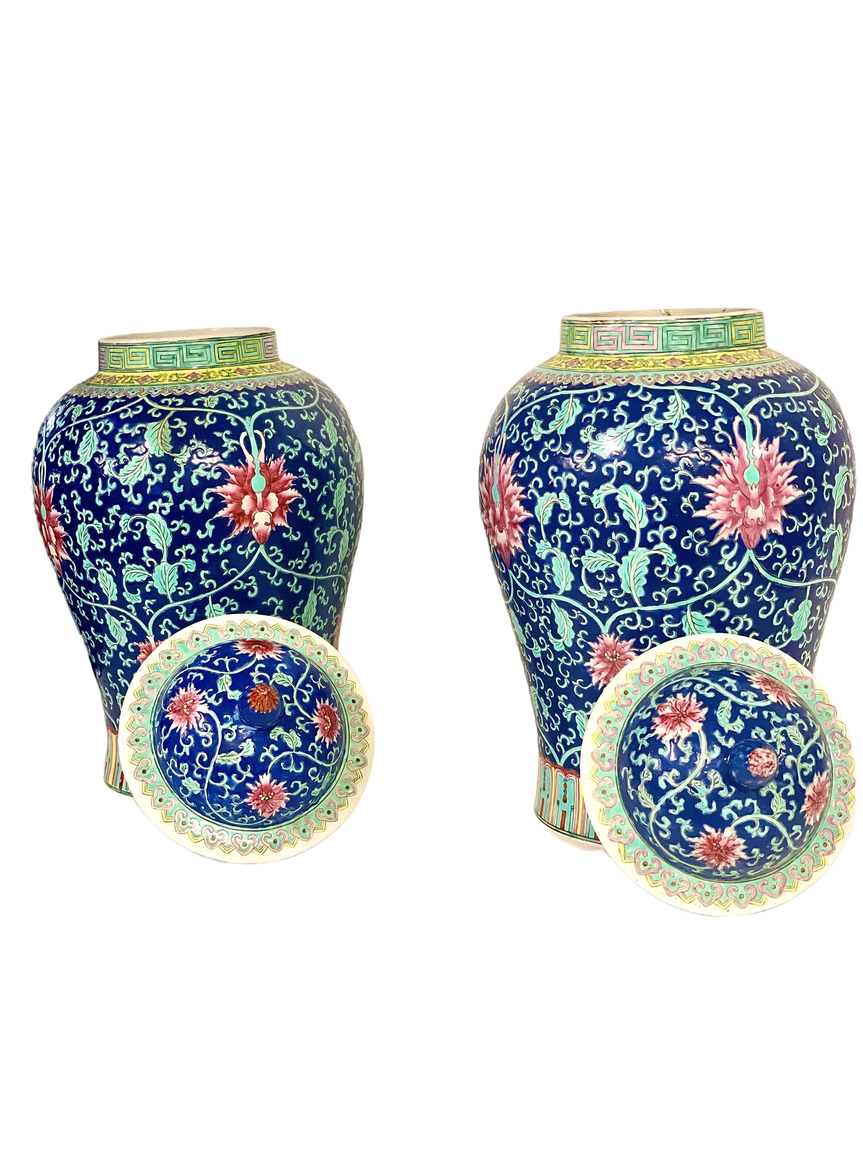 Paire de grands vases de forme balustre finement décorés, datant de la période de la République chinoise, présentant un motif peint à la main aux couleurs vives, composé de pivoines rouges et de feuillage vert pâle sur un fond bleu foncé. Datant du