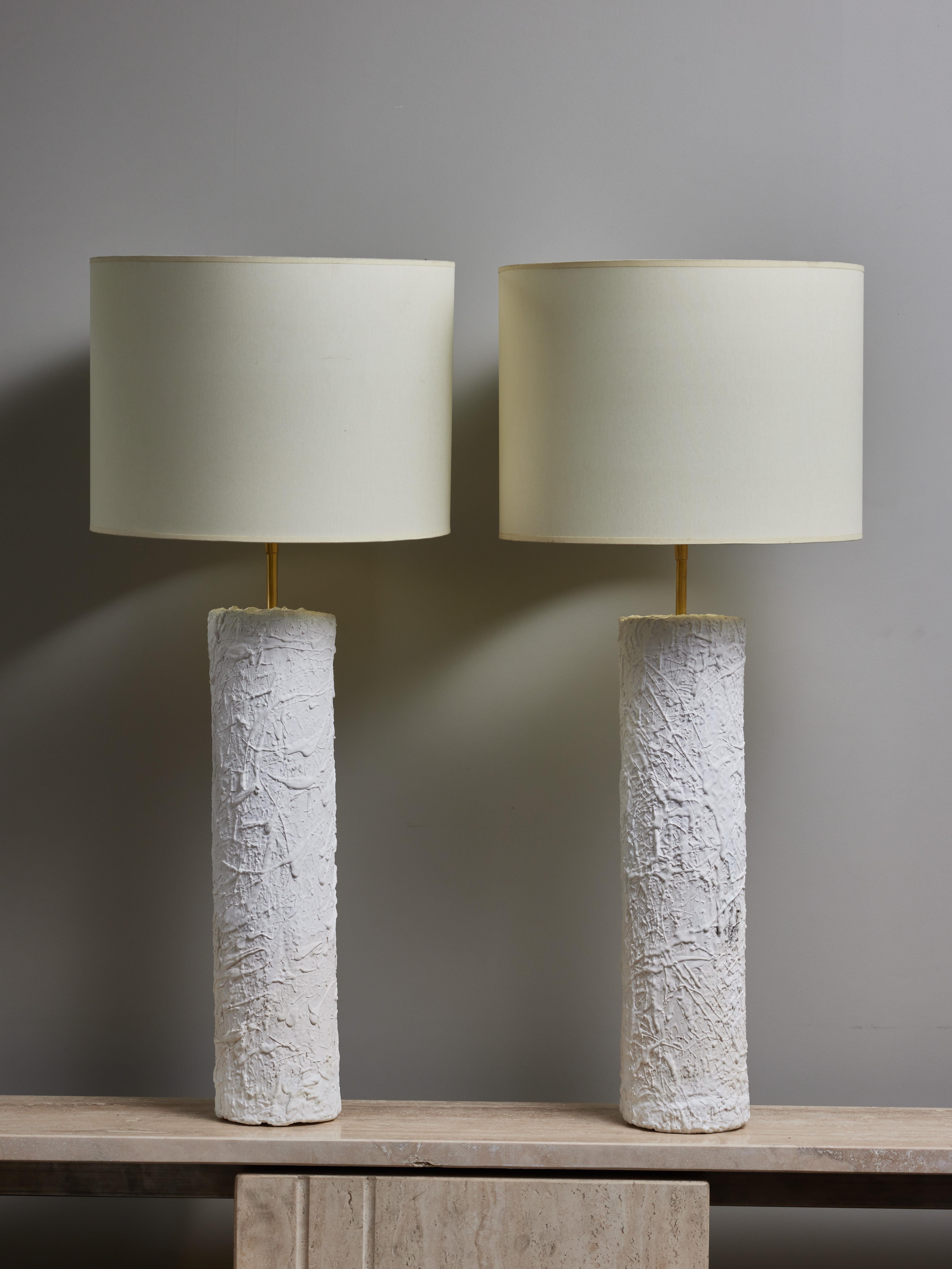 Pair of tall table lamps made of a brass cylinder entirely covered with plaster and finished with a layer of spatter textured plaster. 
