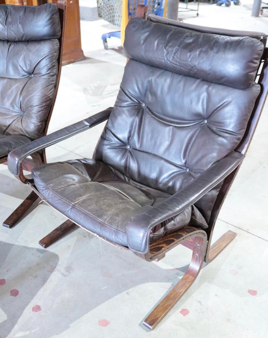 A pair of tall Siesta easy chairs and Footrest of black leather and dark wood, designed by Ingmar Relling and manufactured by Westnofa in the 1960s. The chairs are in great vintage condition.