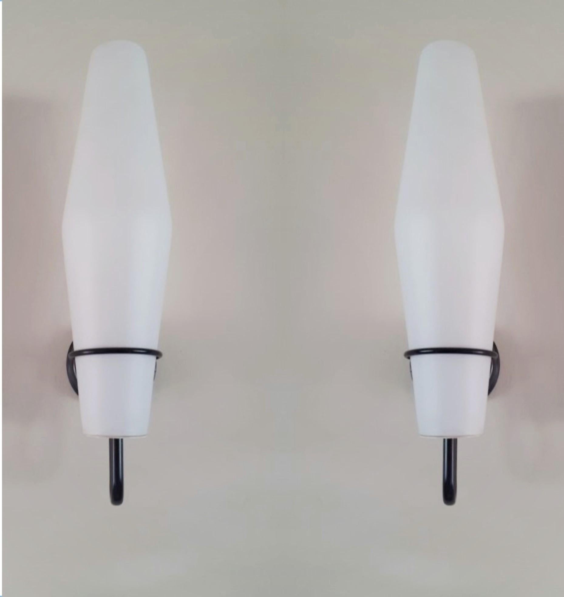 A pair of tall  Scandinavian wall sconces in the Style of Stilnovo, Dänemark, 1960s. Very elegant design with tall satin glass shades and lacquered black metal mounts. Both wall lights in fine vintage condition, no chips or cracks, rewired.
Each