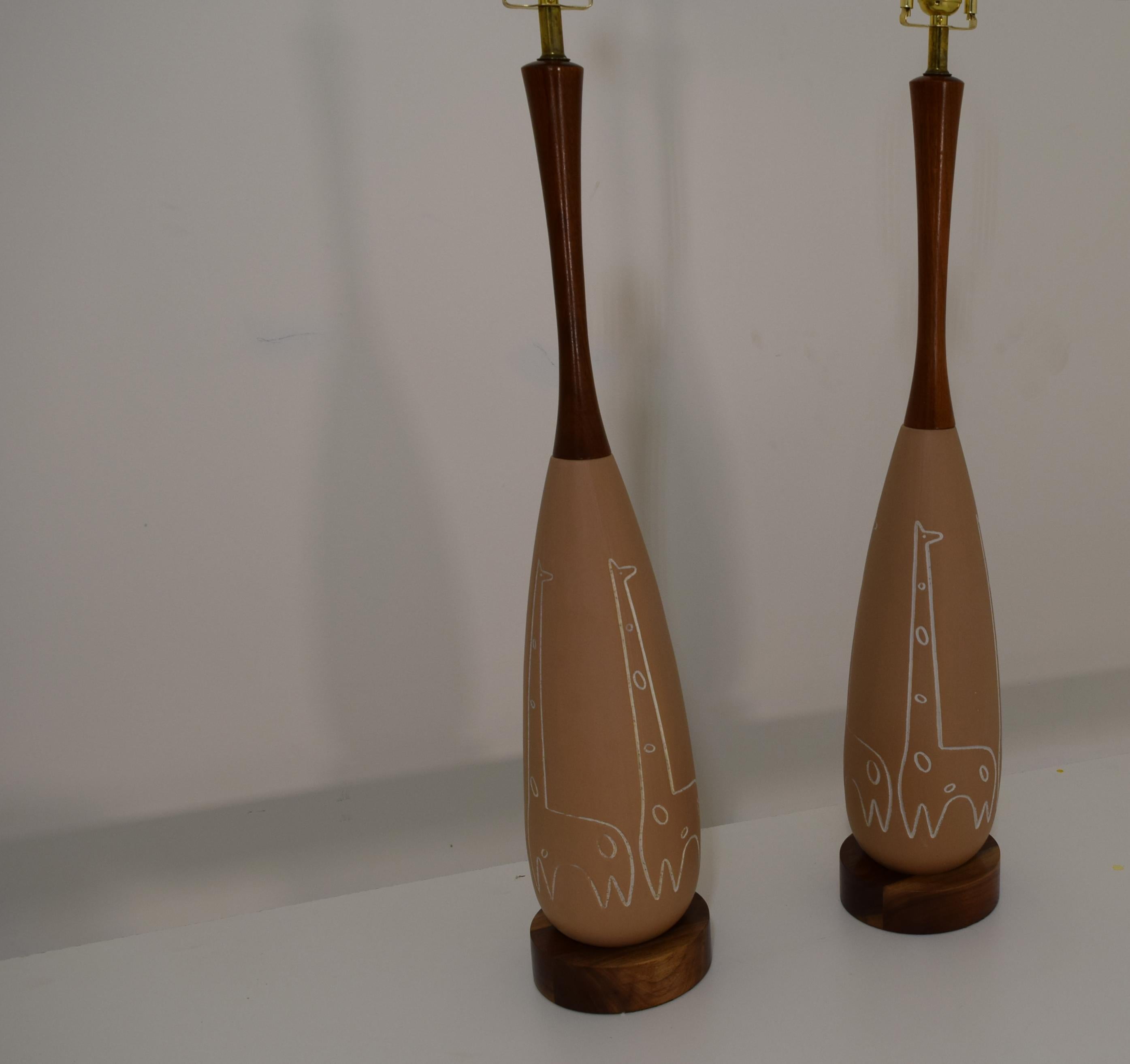 Produced circa 1950, these ceramic table lamps feature an animal motif - giraffes - incised into the ceramic. In excellent condition with the walnut freshly lacquered and the wiring updated as well as 3 way sockets and wiring for each lamp newly