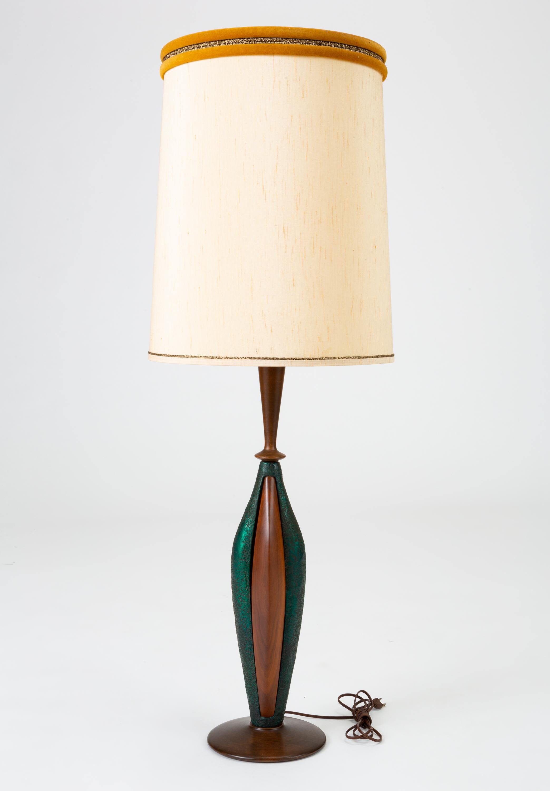 A pair of tall table lamps by the Los Angeles-based Moderna Lamp Manufacturing Co. The lamps have a round base in dark walnut wood, with a slender curved body in a textured teal green resin, with inset walnut ridges. Capped with opulent lampshades