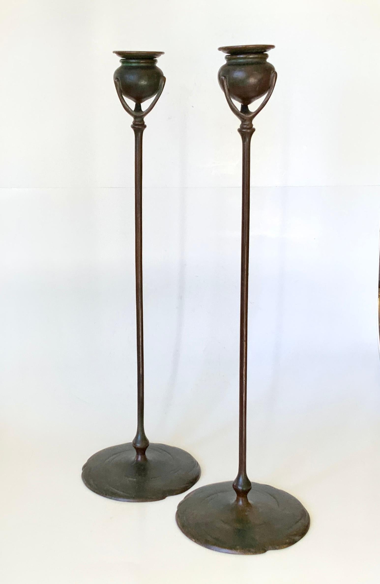 Une belle paire de grands chandeliers en bronze patiné des Studios Tiffany. Les chandeliers sont tous deux signés TIFFANY STUDIOS NEW YORK 1213. Il s'agit d'une paire ancienne, dont la finition patinée d'origine, brun rougeâtre et vert de Tiffany,