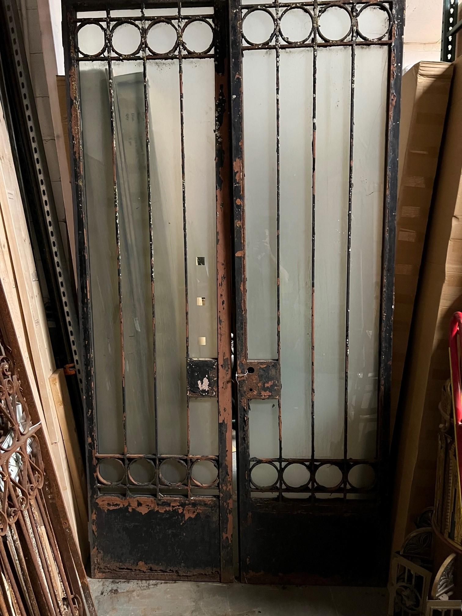 A great pair of tall iron doors with frosted glass panels, very heavy. The doors were salvaged from a building in NYC. They need to be cleaned, painted and the bottom of the doors needs to be repair from rust damage. Overall they are very sturdy