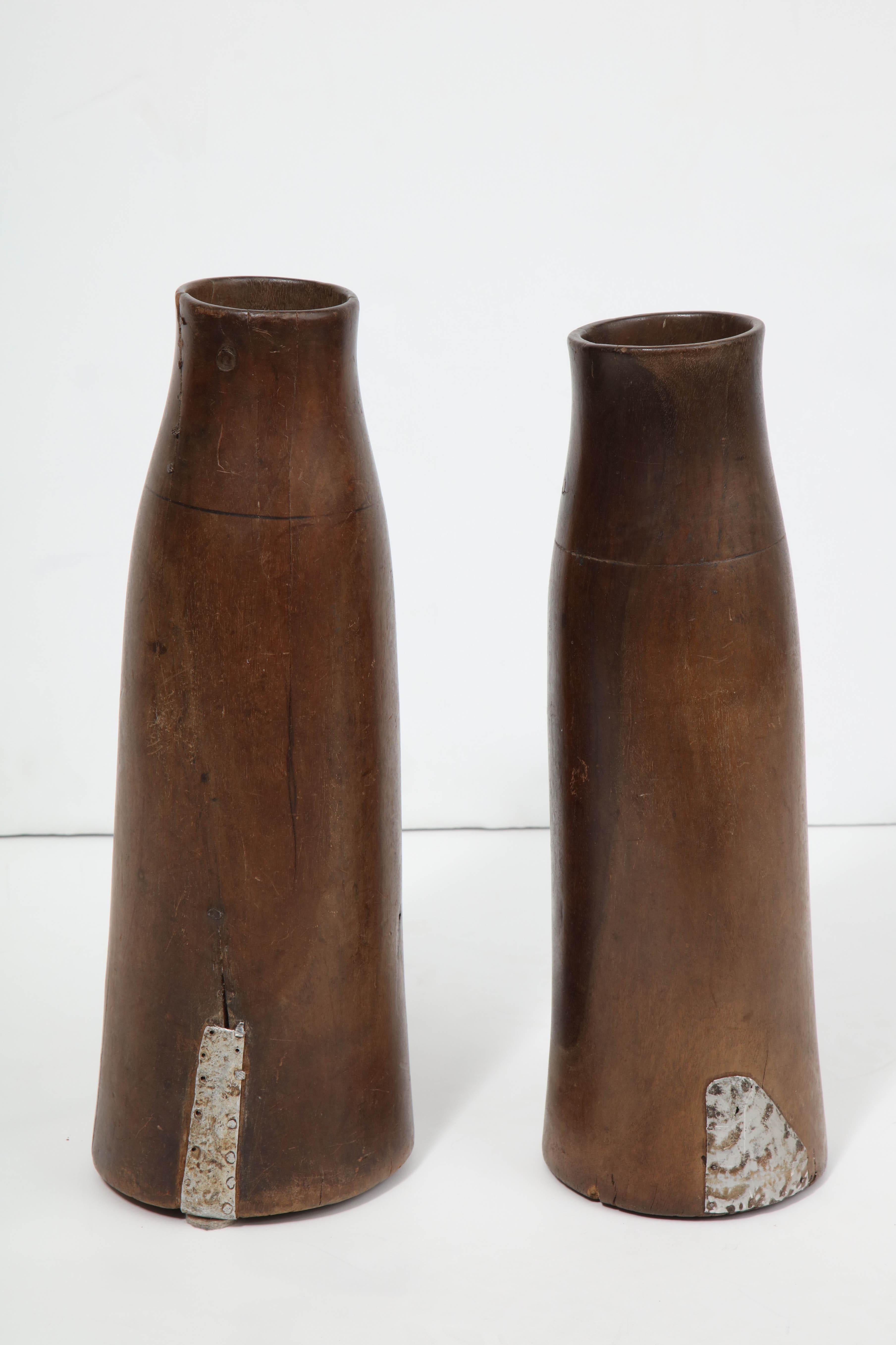 Hand-carved tall wooden milk holders with metal inserts.