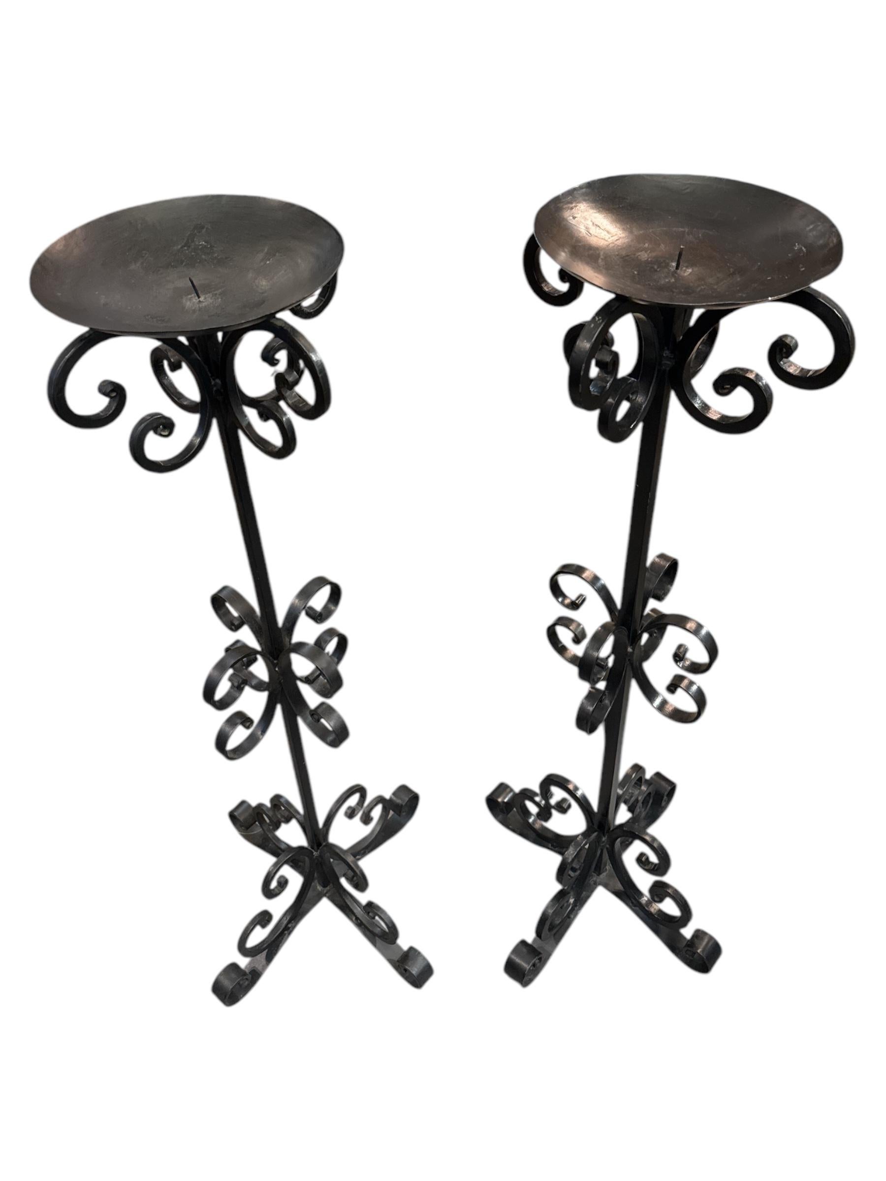 Add a touch of timeless elegance to your home with this Pair of Tall Wrought Iron Curly Floor Candle Holders. Expertly handcrafted, these striking candle stands feature gracefully curved ironwork, offering a perfect blend of classic charm and modern
