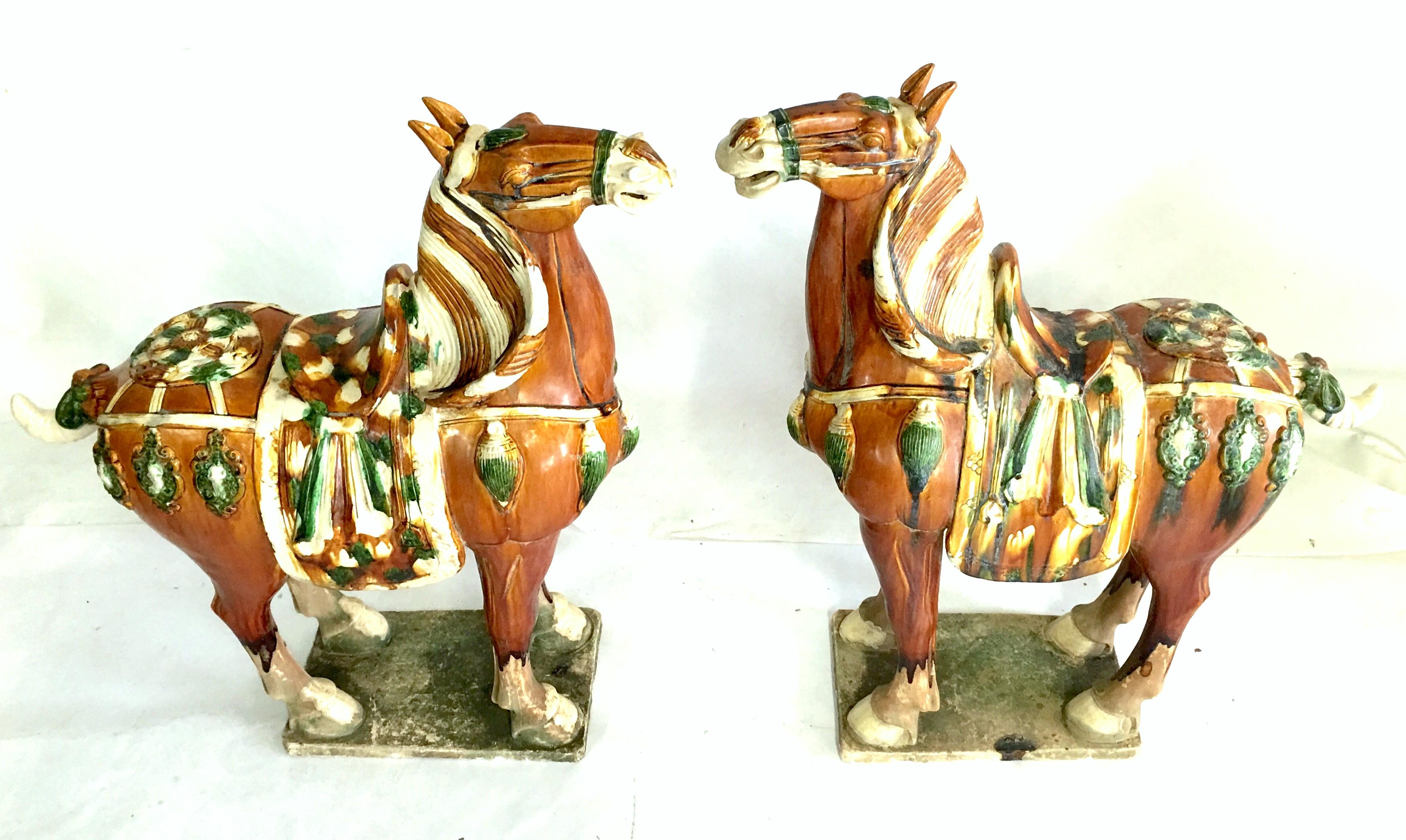 Mid-20th century pair of floor size Tang dynasty style horse sculptures. This pair of beautiful terracotta horses are handmade and painted using the ancient tri-glaze techniques.
    