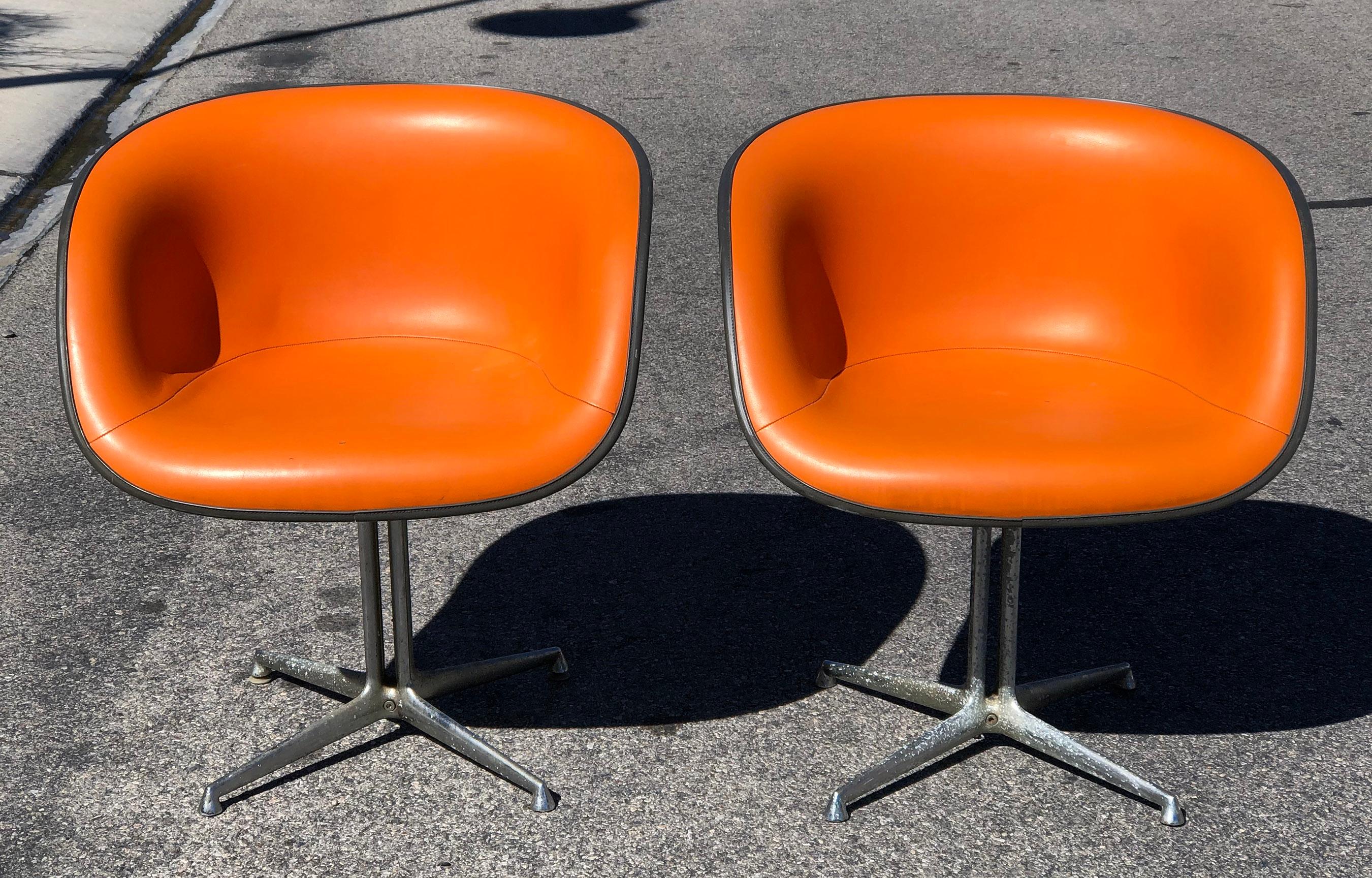 An absolutely gorgeous pair of Eames La Fonda chairs, circa 1960. These bright tangerine colored chairs both still retain their original tags, however the dates have faded off. A great pair of iconic chairs! 

Condition notes: The chairs are in