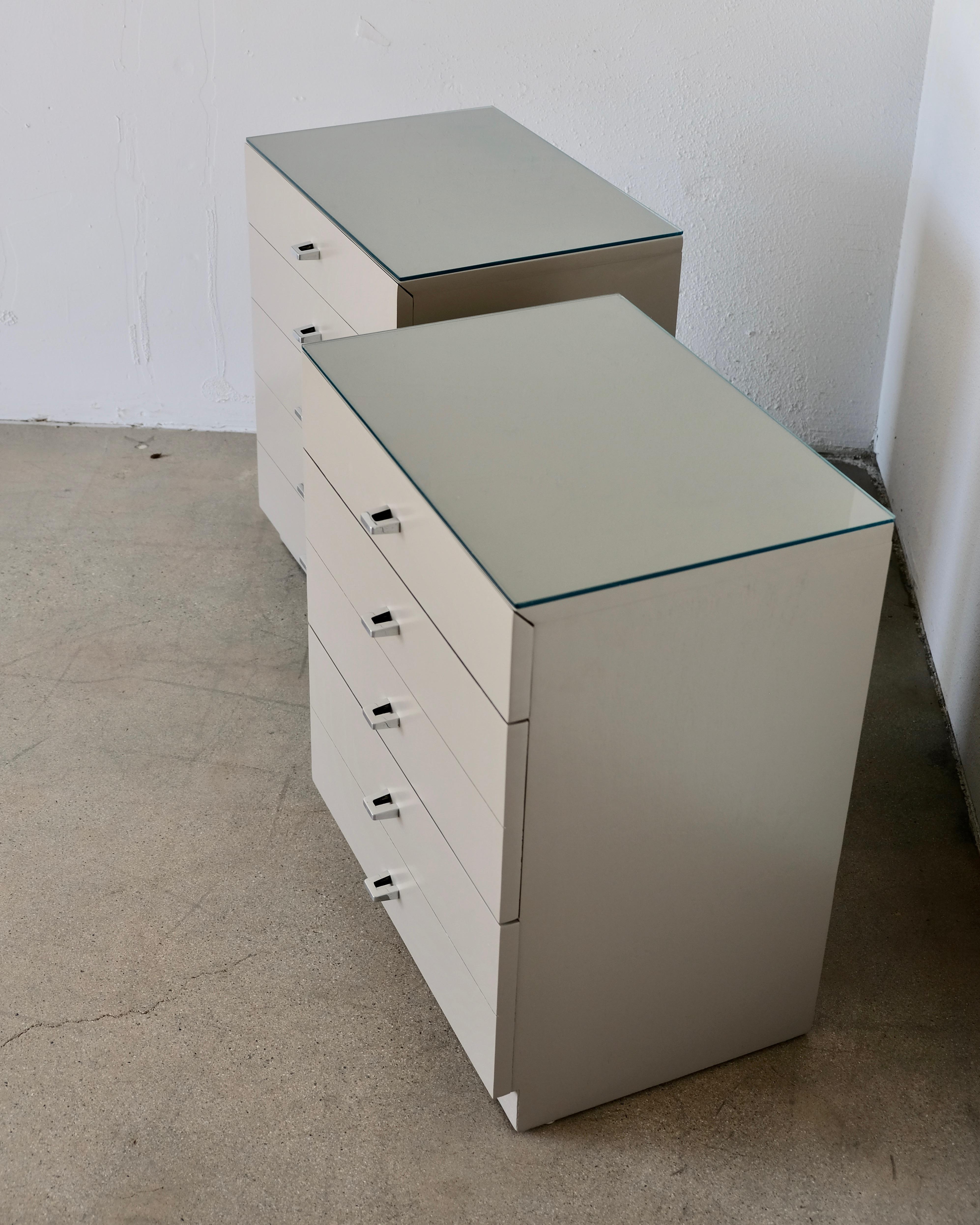 A pair of American of Martinsville bedside tables or nightstands that have been refinished in a light taupe. The original hardware has been professionally polished. 
Each chest has three drawers. The top drawer is more shallow while the bottom two