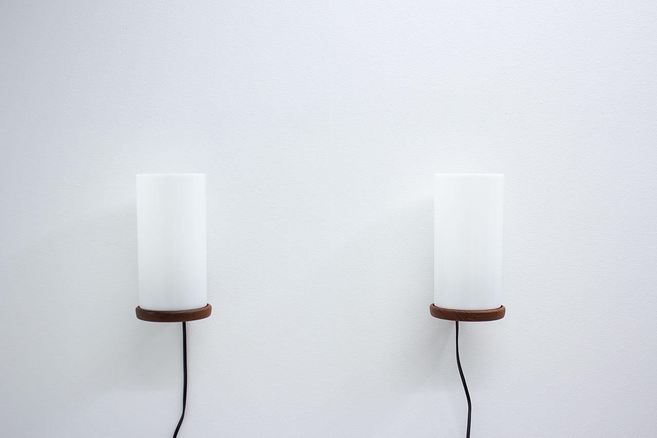Coppia di lampade da parete disegnate dai fratelli Uno & Östen Kristiansson per la loro azienda LUXUS. Prodotto a Vittsjö in Svezia tra la fine degli anni '50 e l'inizio degli anni '60. Le applique sono realizzate con raccordi in teak e diffusore in