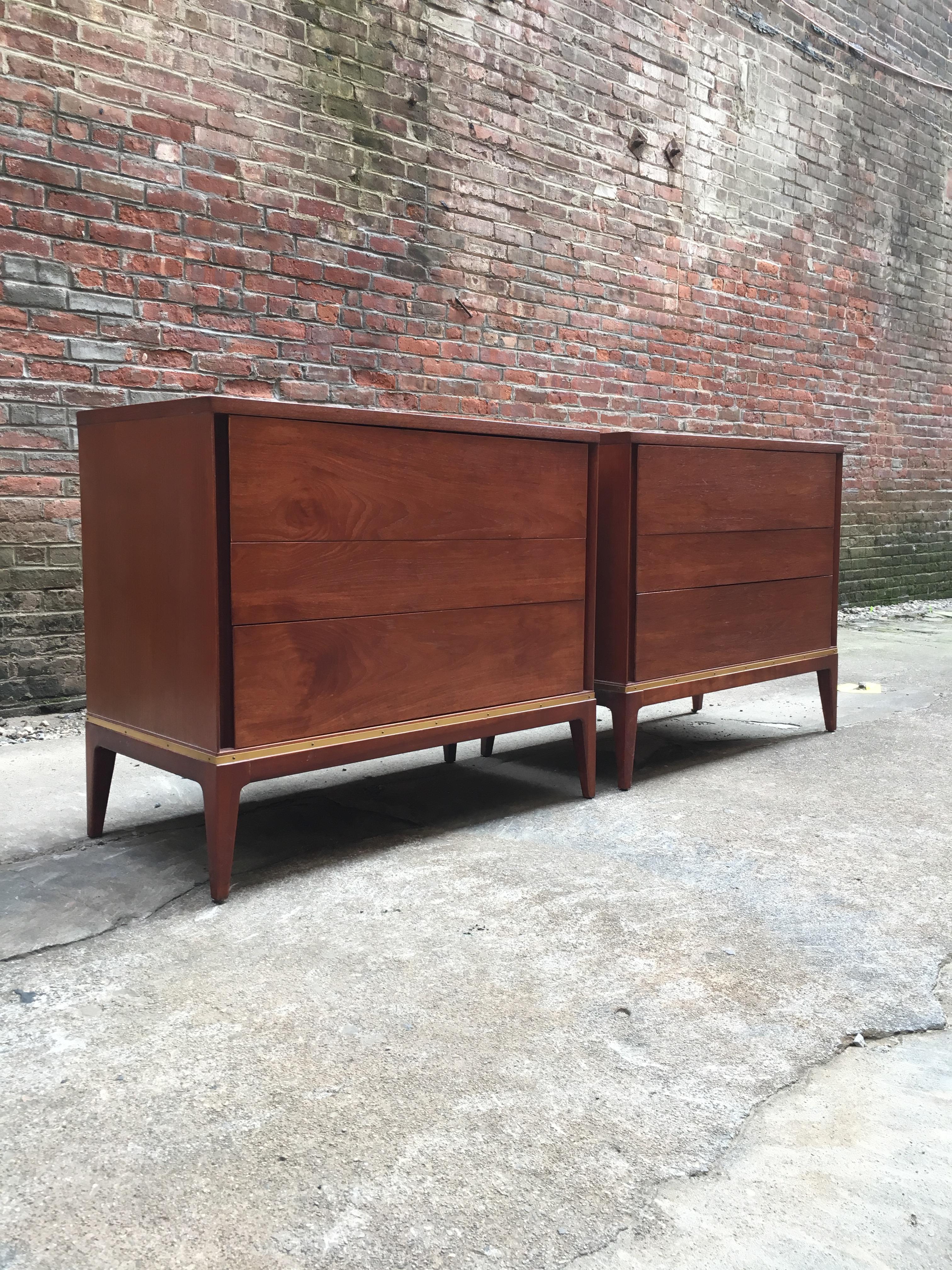 Pair of teak with brass detail three-drawer dressers retailed for John Stuart. True sign of quality when a piece of furniture has the John Stuart medallion in the top drawer. Warm teak with brass detail around the base. Featuring solid tapered legs