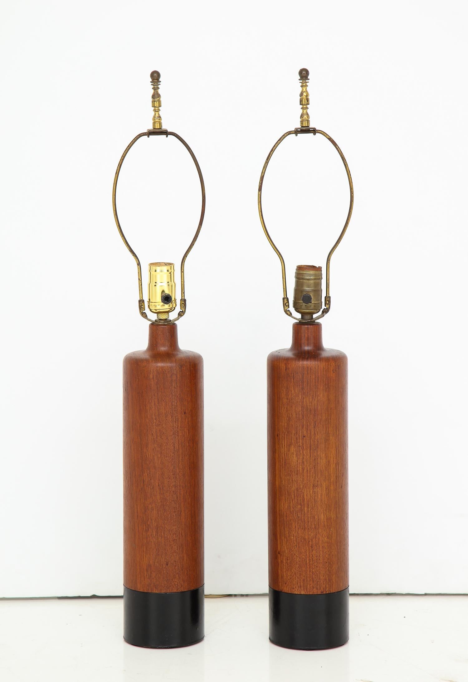 Pair of cylindrical teak lamps with narrow necks and hand-stitched leather wrapped bottoms. By ESA, Denmark, circa 1960s. Measurements of wooden part only; height to the top of finial is 27