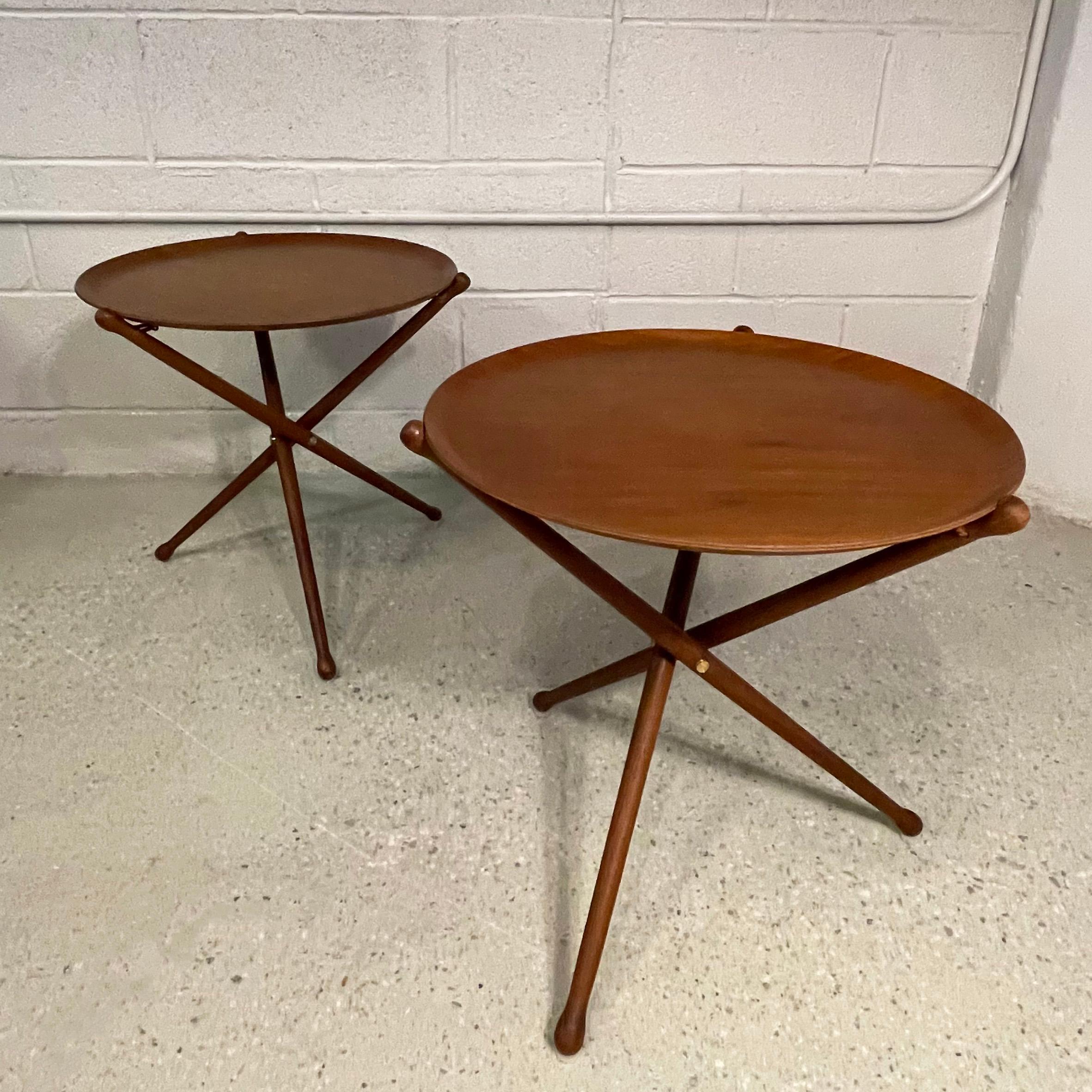 Pair of Scandinavian modern, teak, folding, tray tables by Nils Trautner for Ary Nybro, Sweden feature collapsible, leather strung, tripod bases that accept 17.5 inch round tray surfaces. The tables fold completely to store away and are very sturdy
