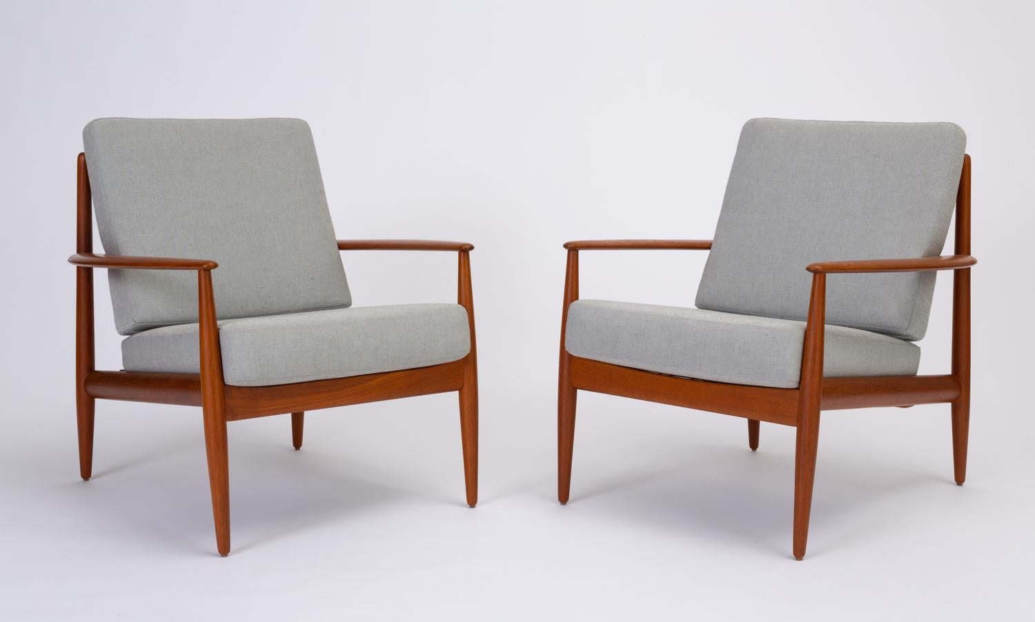 An elegant pair of Model 128 lounge chairs designed by Grete Jalk for France & Son in 1963. The chair has an elongated seat framed by broad, boomerang-reminiscent armrests. The open back of the chair is described by four organically curved slats.