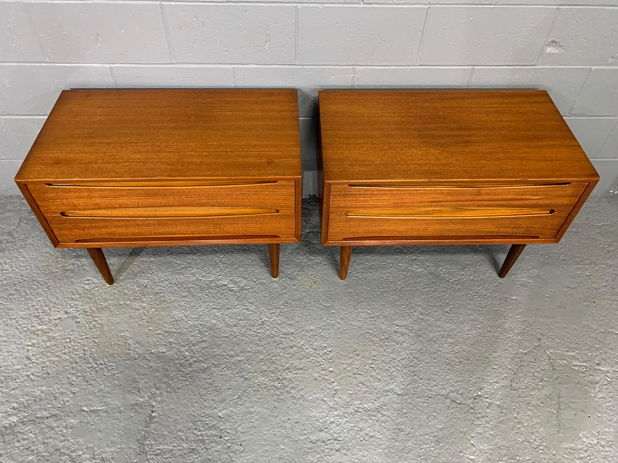 Handsome pair of teak Danish modern midcentury nightstands / end tables. Each piece has two drawers with handles elegantly crafted into the solid teak drawer front. Dovetailed joinery on each drawers.