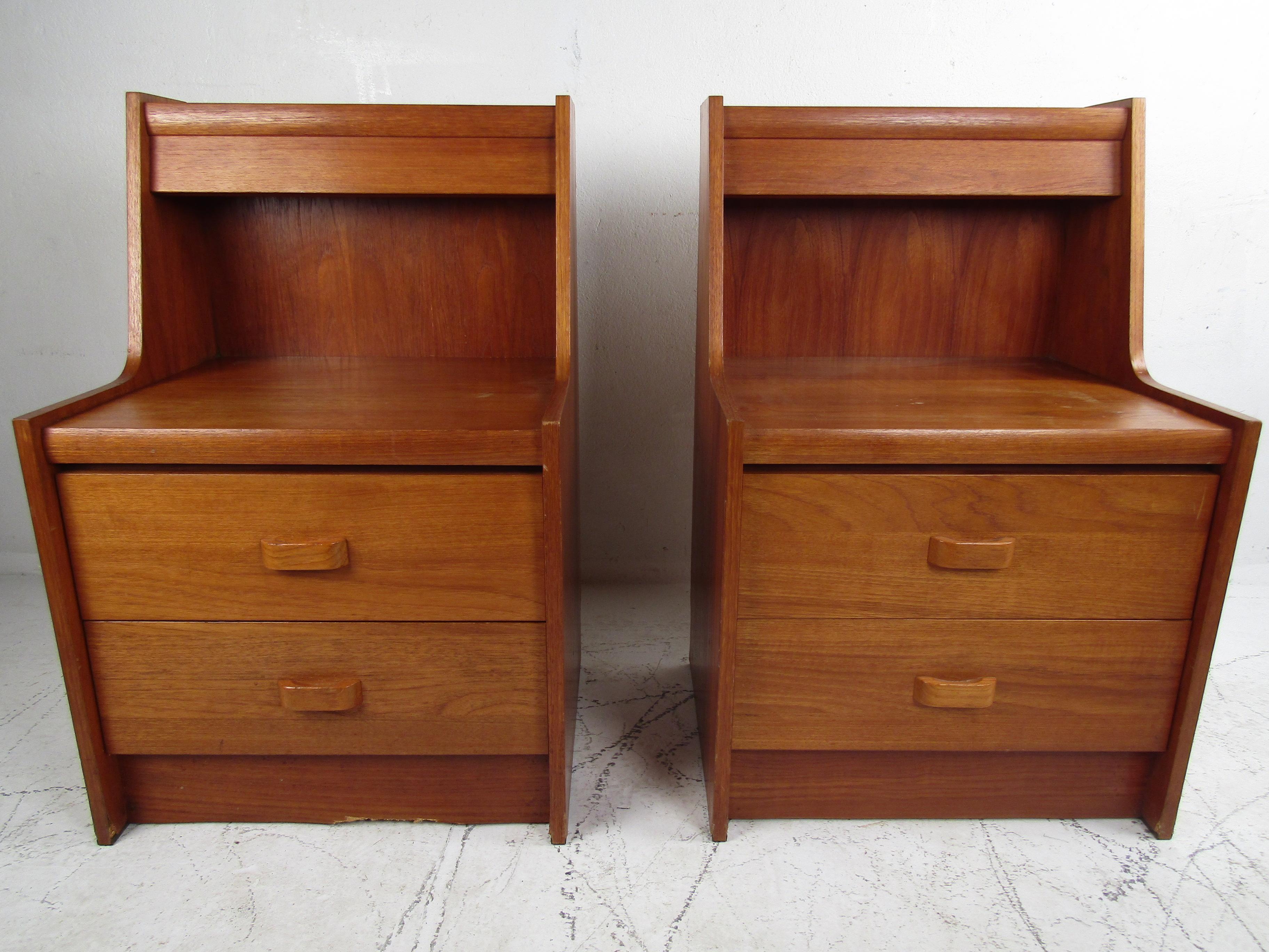 Nice pair of midcentury nightstands made by the French-Canadian manufacturer R.S. Furniture. Teak veneer exterior. Two drawers with sculpted pulls on each piece. Additionally, each stand has a light fixture attached to the apex of the case's frame.