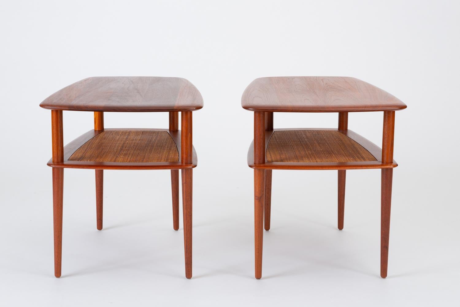 A pair of teak side tables made by France & Daverkosen for retail in the US by John Stuart. Designed by Peter Hvidt and Orla Mølgaard-Nielsen and produced in 1956, these tall tables have a rounded, trapezoidal surface in solid teak with slightly