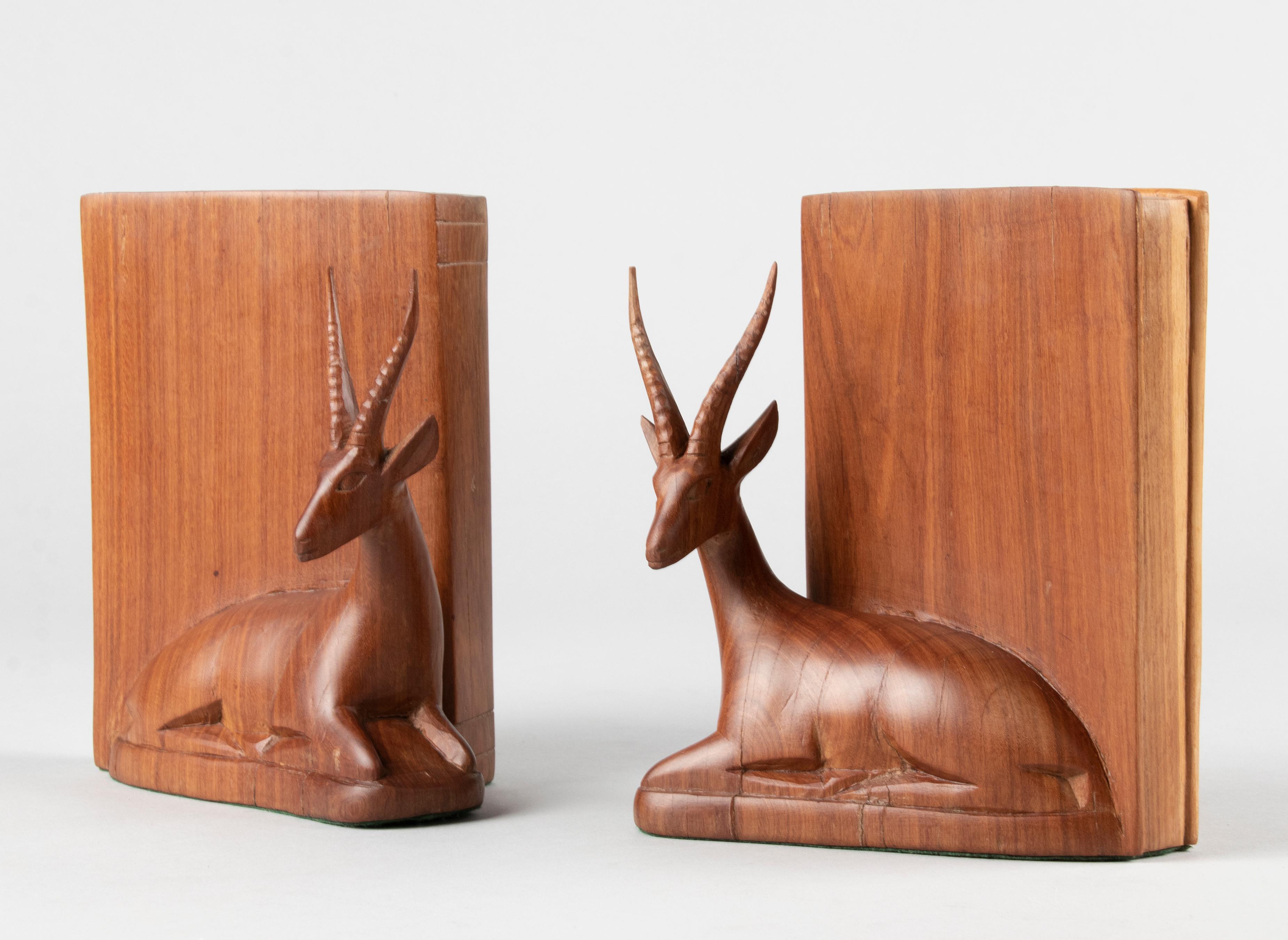 A beautiful pair of vintage bookends from the 1960s / 1970s. The bookends are made of teak wood, with carved works of deer or ibex. The supports themselves are shaped like books (stylized). These objects are bottom lined with green felt. One of the