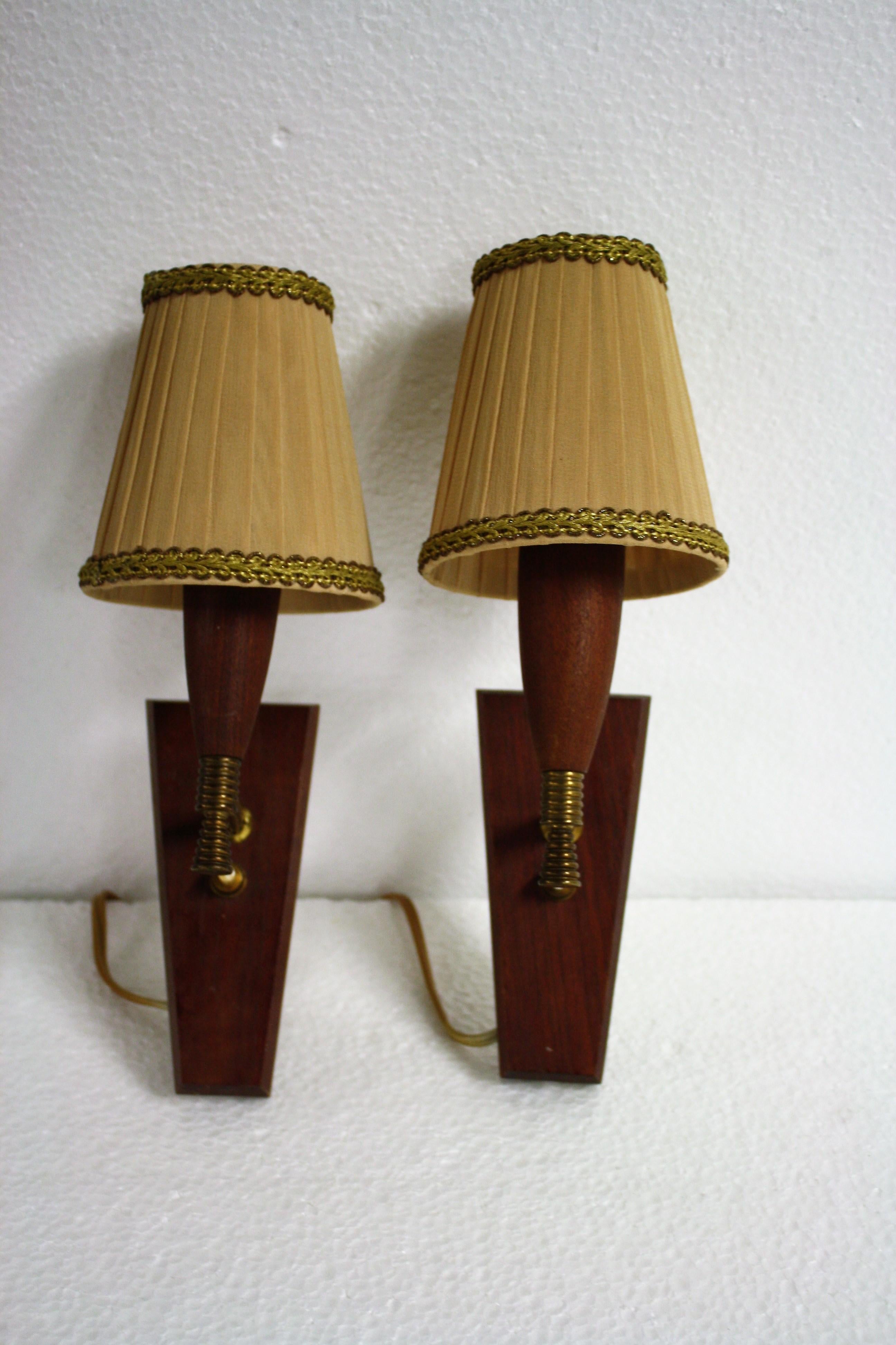 Classic and finely manufactured brass and teak wooden candle light sconces.

These lovely wall lights come with their original clip on lamp shades. But in a more modern day interior they'd look just fine without them.

Very good condition with