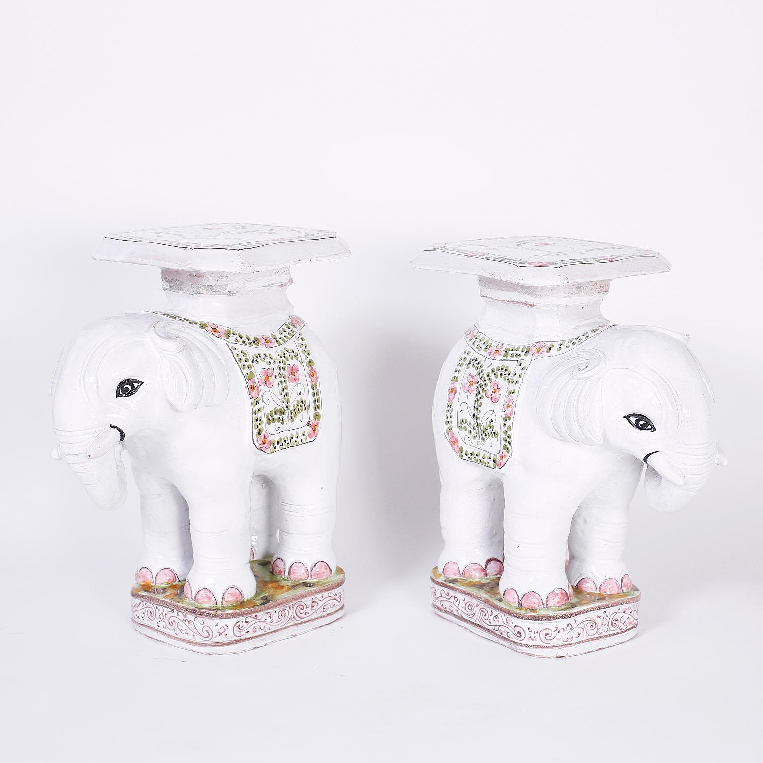 Pair of terracotta elephant tables or stands with a white glaze decorated with happy floral designs.
