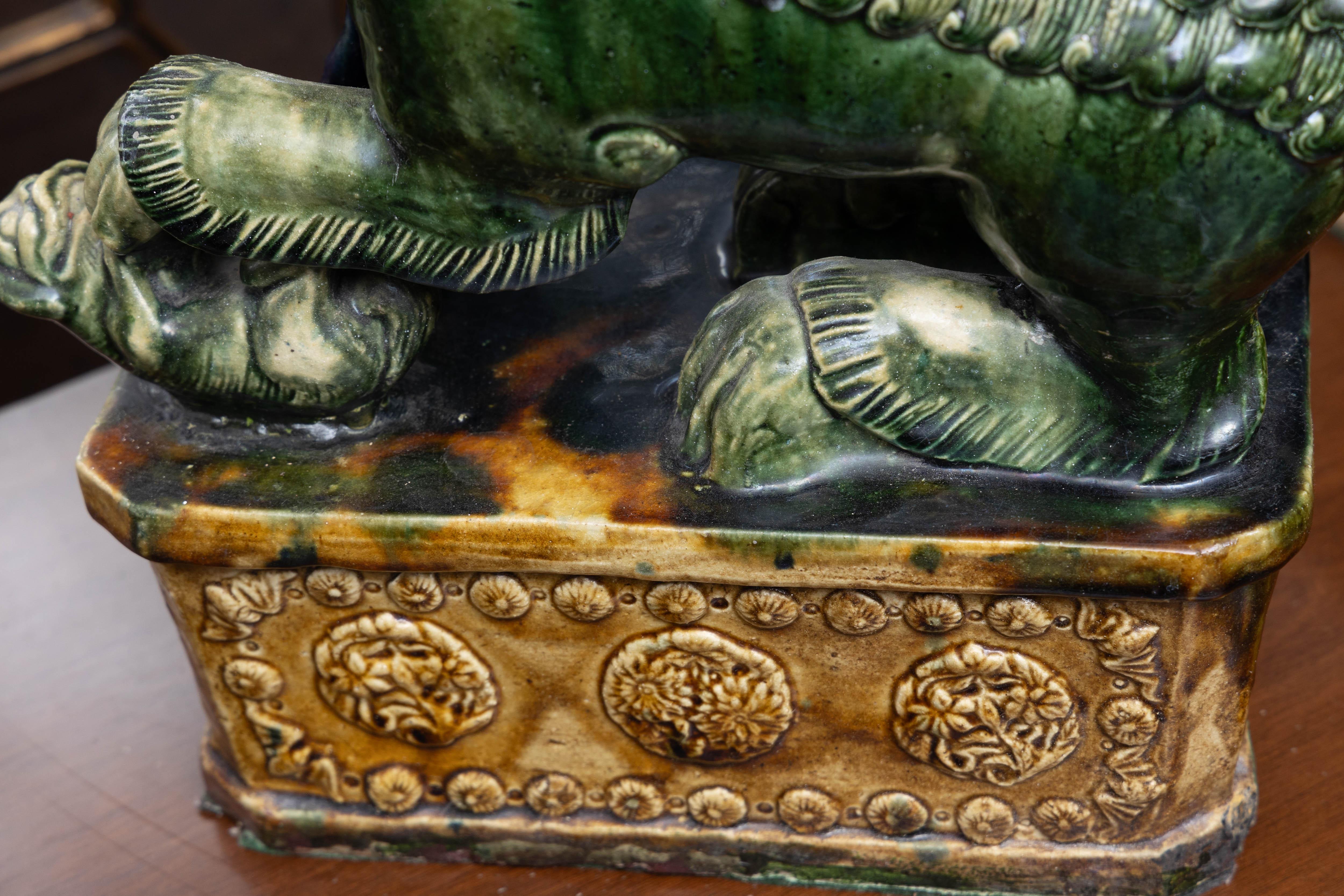 This is a dramatic, colorful large pair of Chinese foo dogs hand painted in rich tones of green, blue and gold, 20th century.