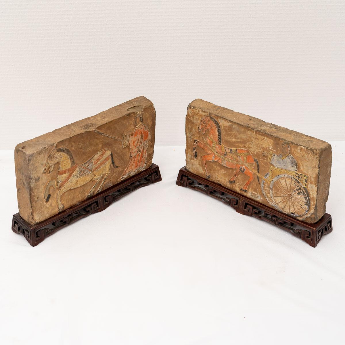 Pair of terracotta bricks with traces of polychromy representing for one a character driving his chariot drawn by a horse and for the other a character training his horse.

These two bricks are exposed on their original carved wooden bases.

Period